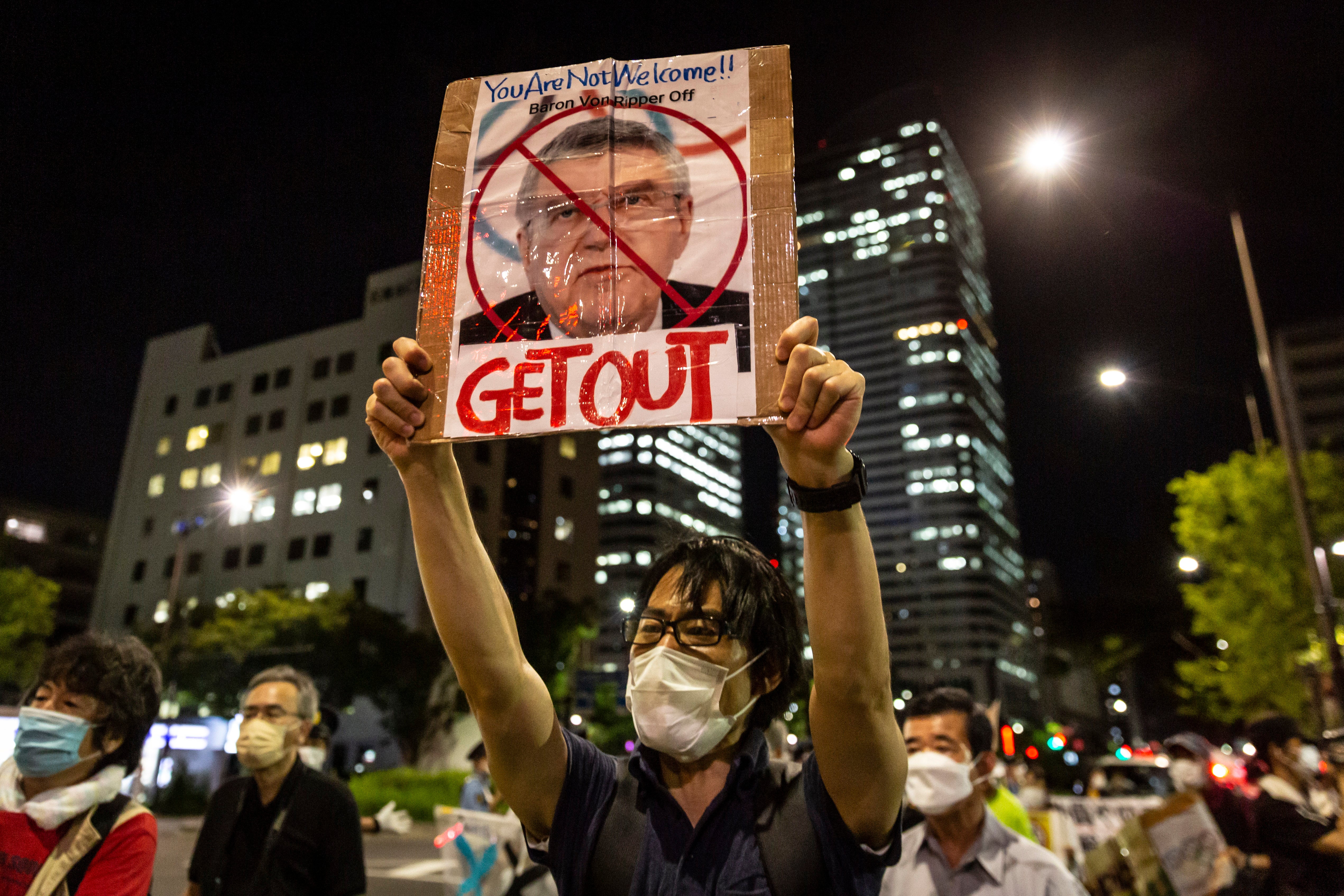 A protester holds up a placard with a picture of IOC president Thomas Bach during a demonstration in Tokyo against the forthcoming Olympics