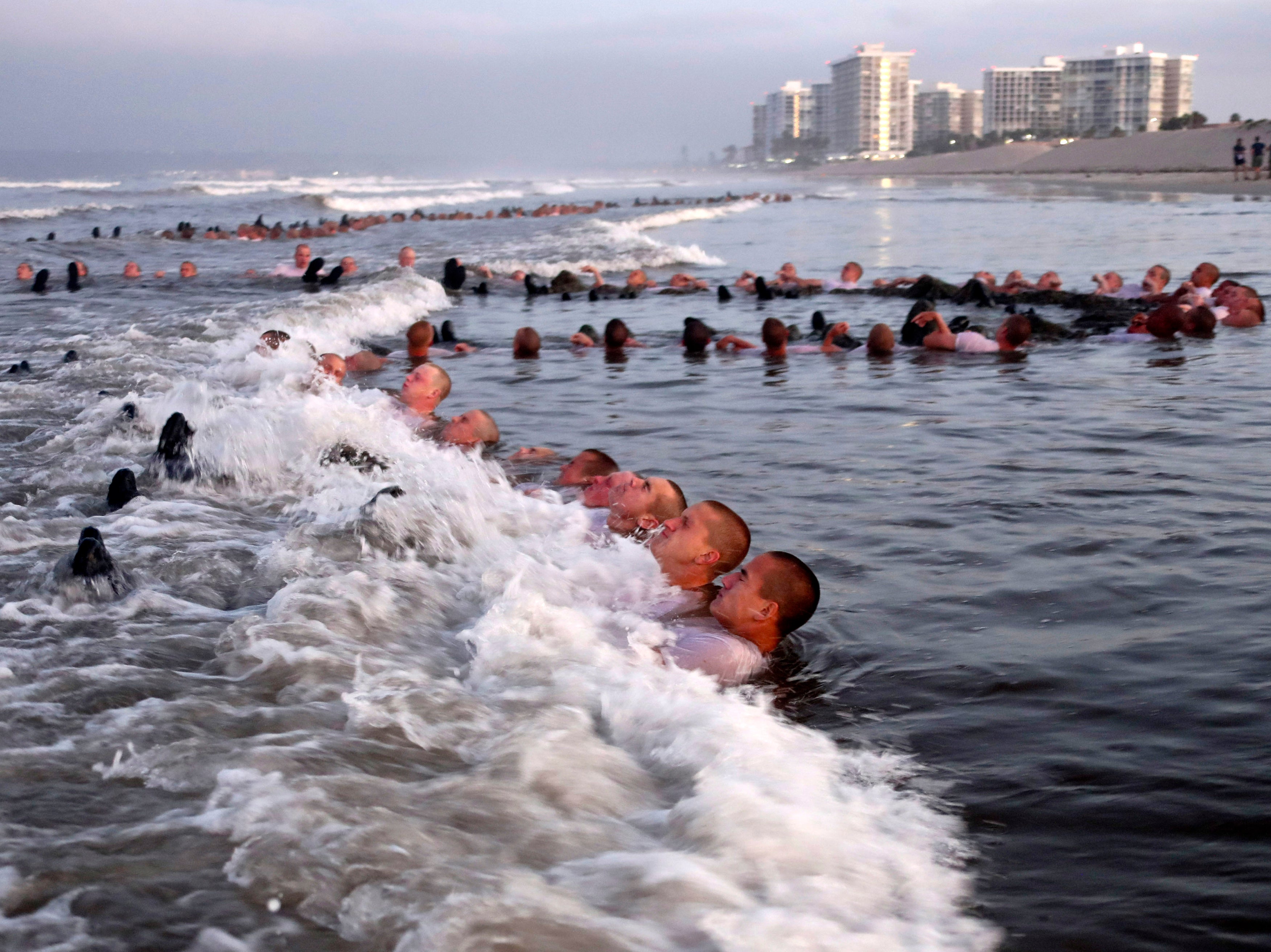 In this May 4, 2020 photo provided by the US Navy, SEAL candidates participate in “surf immersion” during Basic Underwater Demolition training.