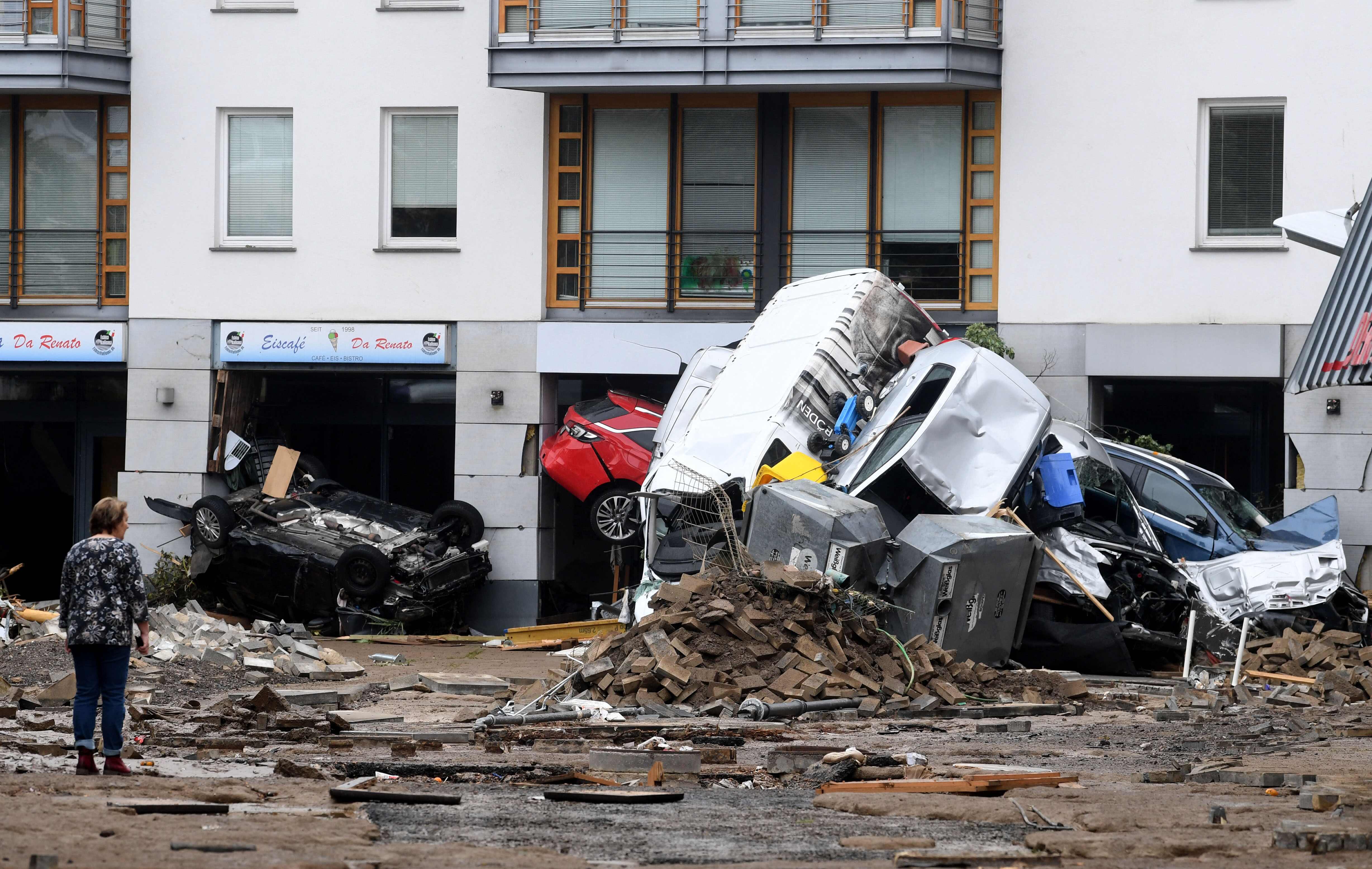 A woman looks at cars and rubble piled up in a street after the floods caused major damage in Bad Neuenahr-Ahrweiler, western Germany