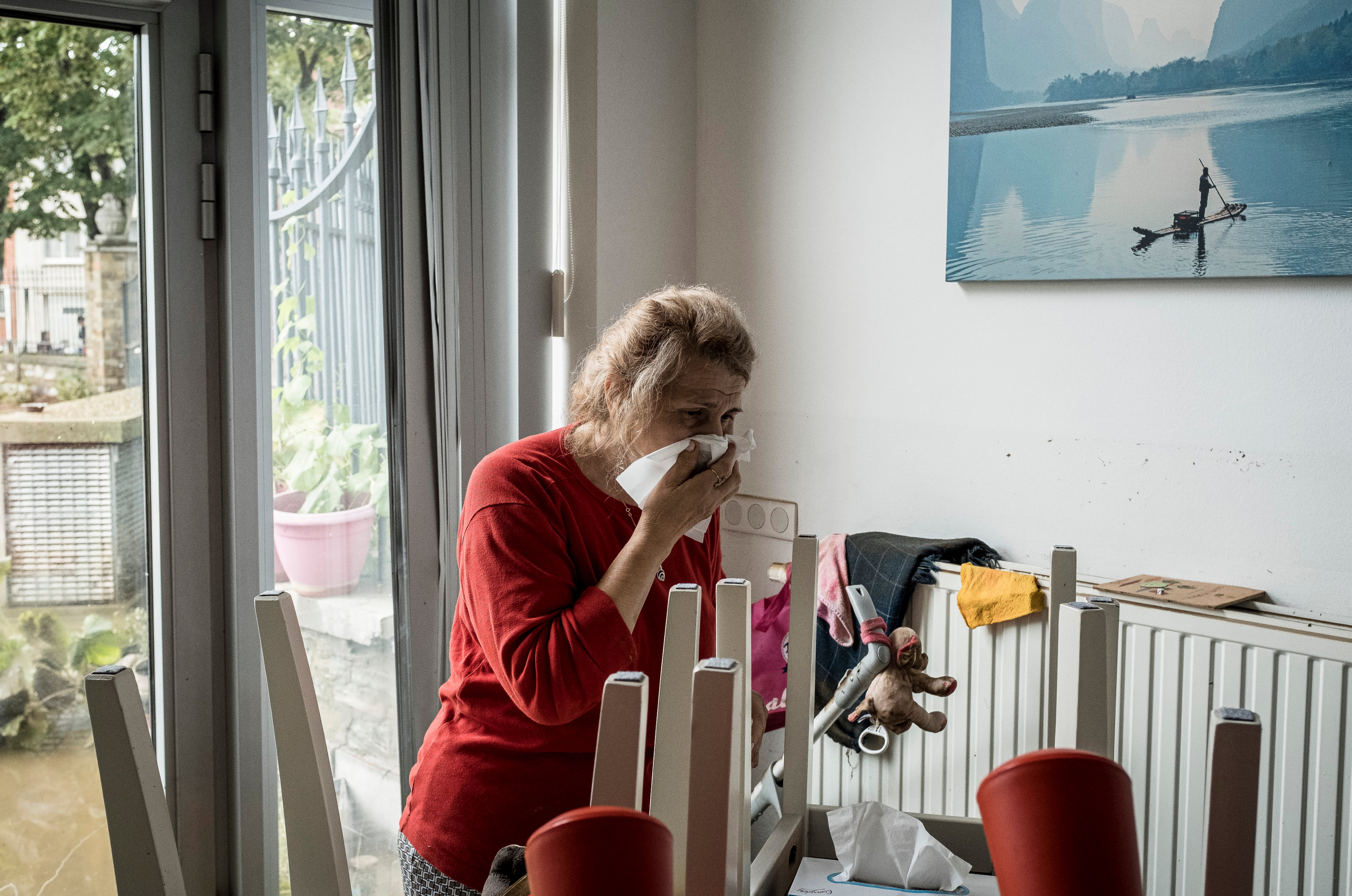 A woman reacts as she walks into her house after flooding