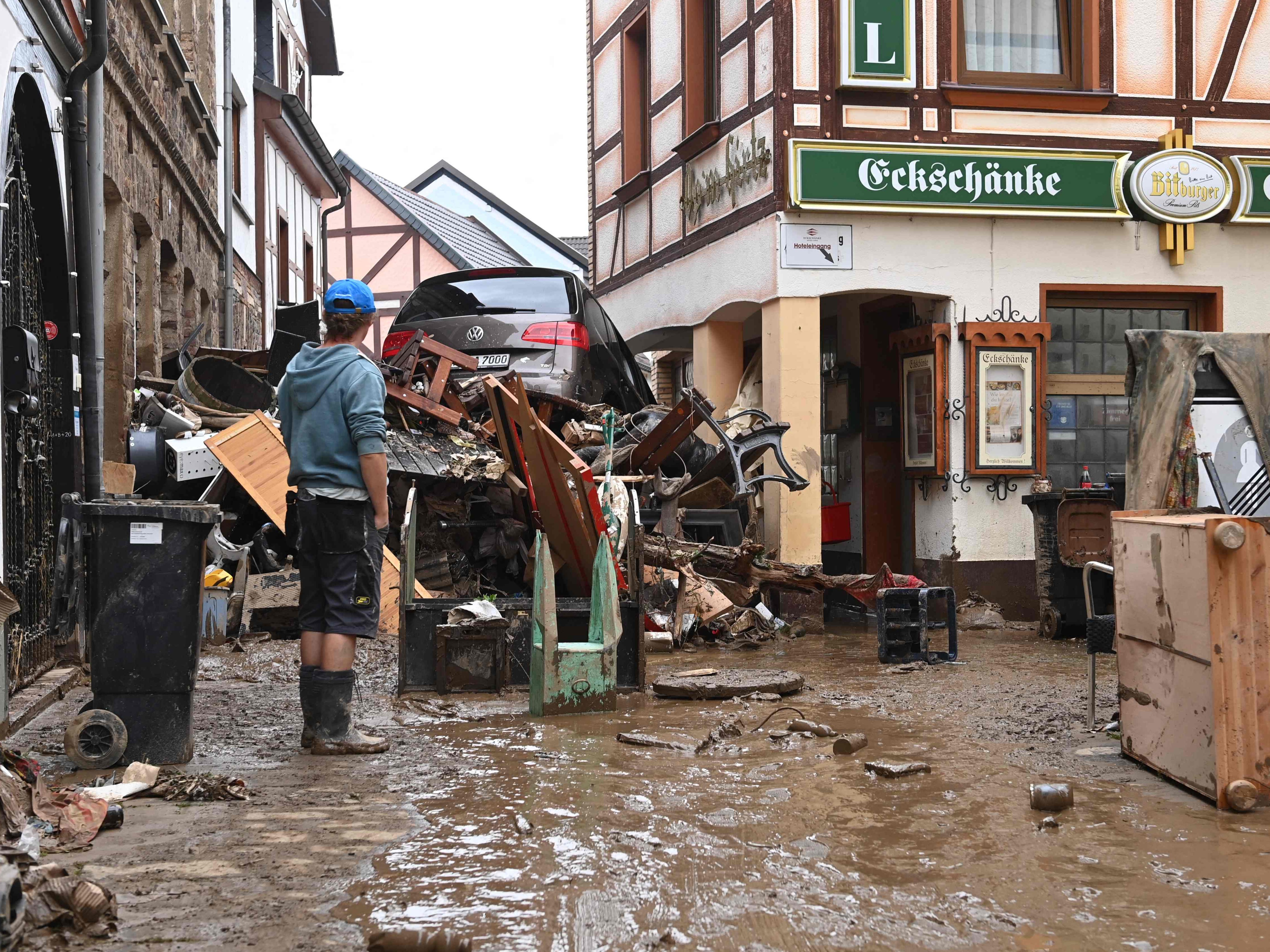 A local resident stands next to debris and a damaged car in a street in Bad Neuenahr-Ahrweiler, western Germany,