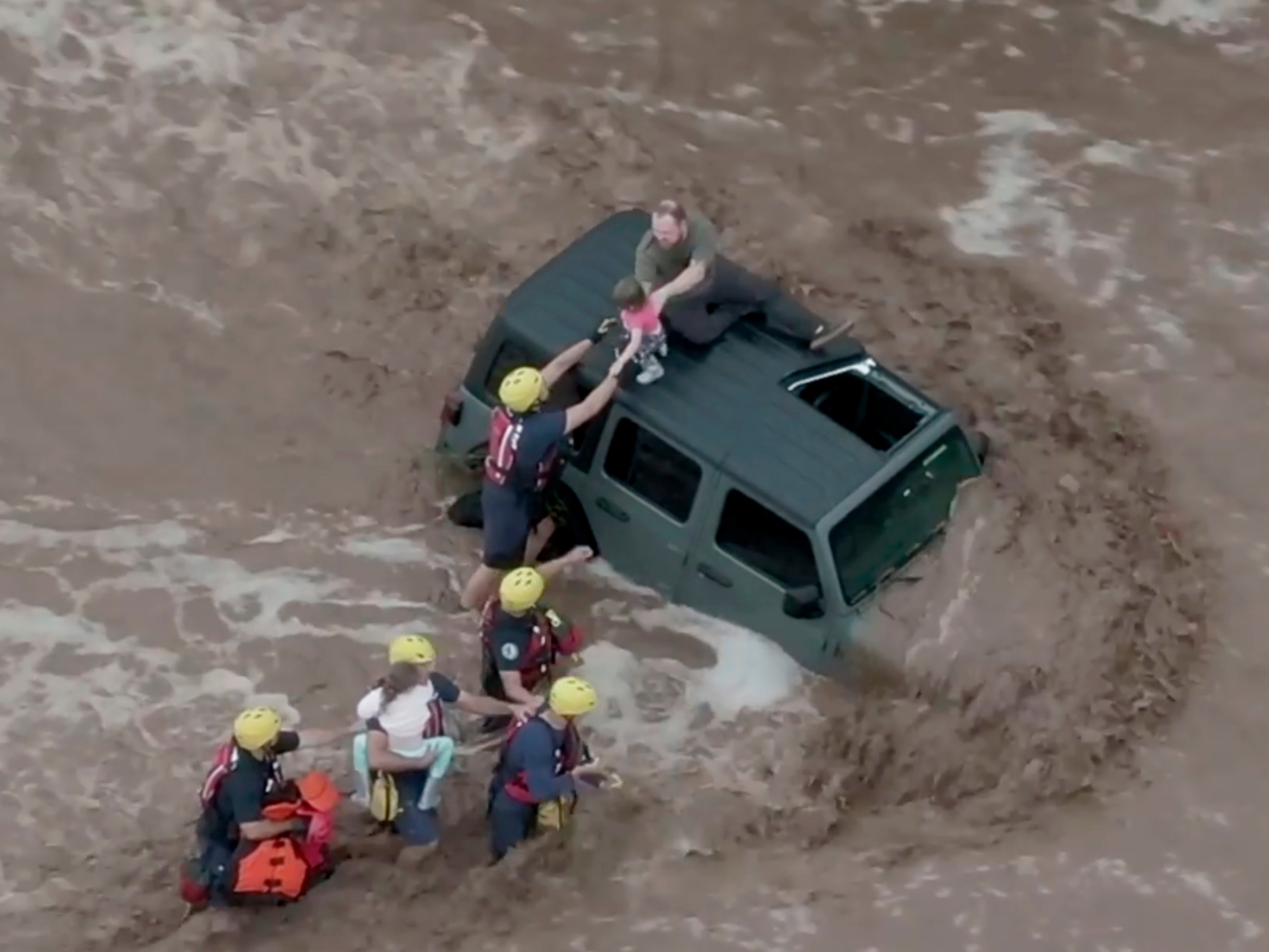 <p>Drone image shows firefighters safely rescue a man and his two daughters from the roof of their vehicle in flash floods north of Tucson, Arizona</p>