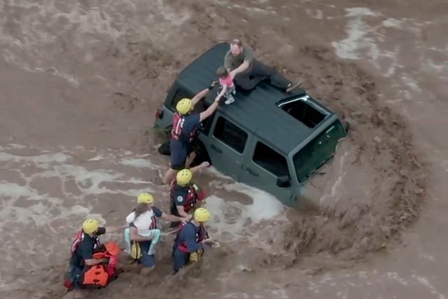 <p>Drone image shows firefighters safely rescue a man and his two daughters from the roof of their vehicle in flash floods north of Tucson, Arizona</p>