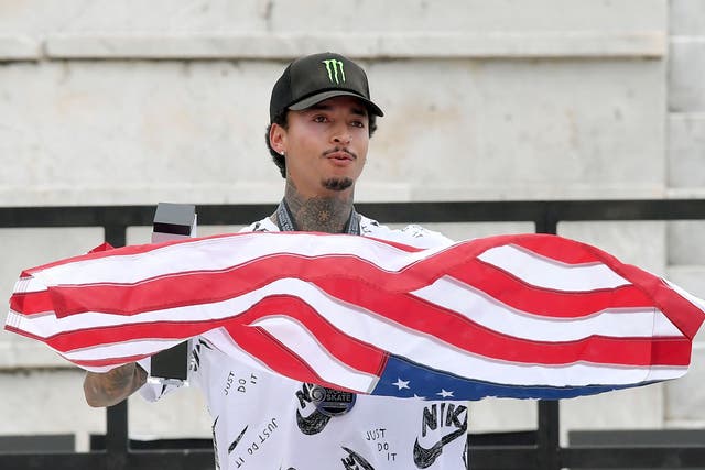 <p>Runner-up US skateboarder Nyjah Huston poses with the US flag on the podium after the Men's Final of the Street World Championships 2021 street skateboarding event on June 06, 2021 at Foro Italico in Rome. </p>