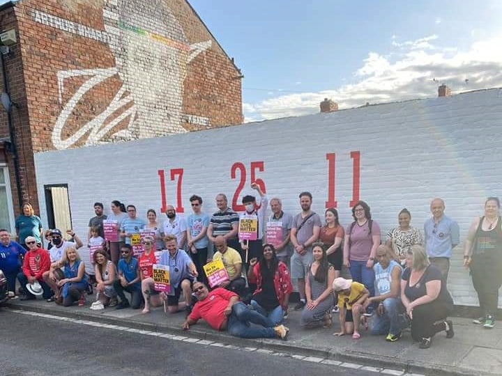 Anti-racism campaigners take the knee in front of the newly repainted mural