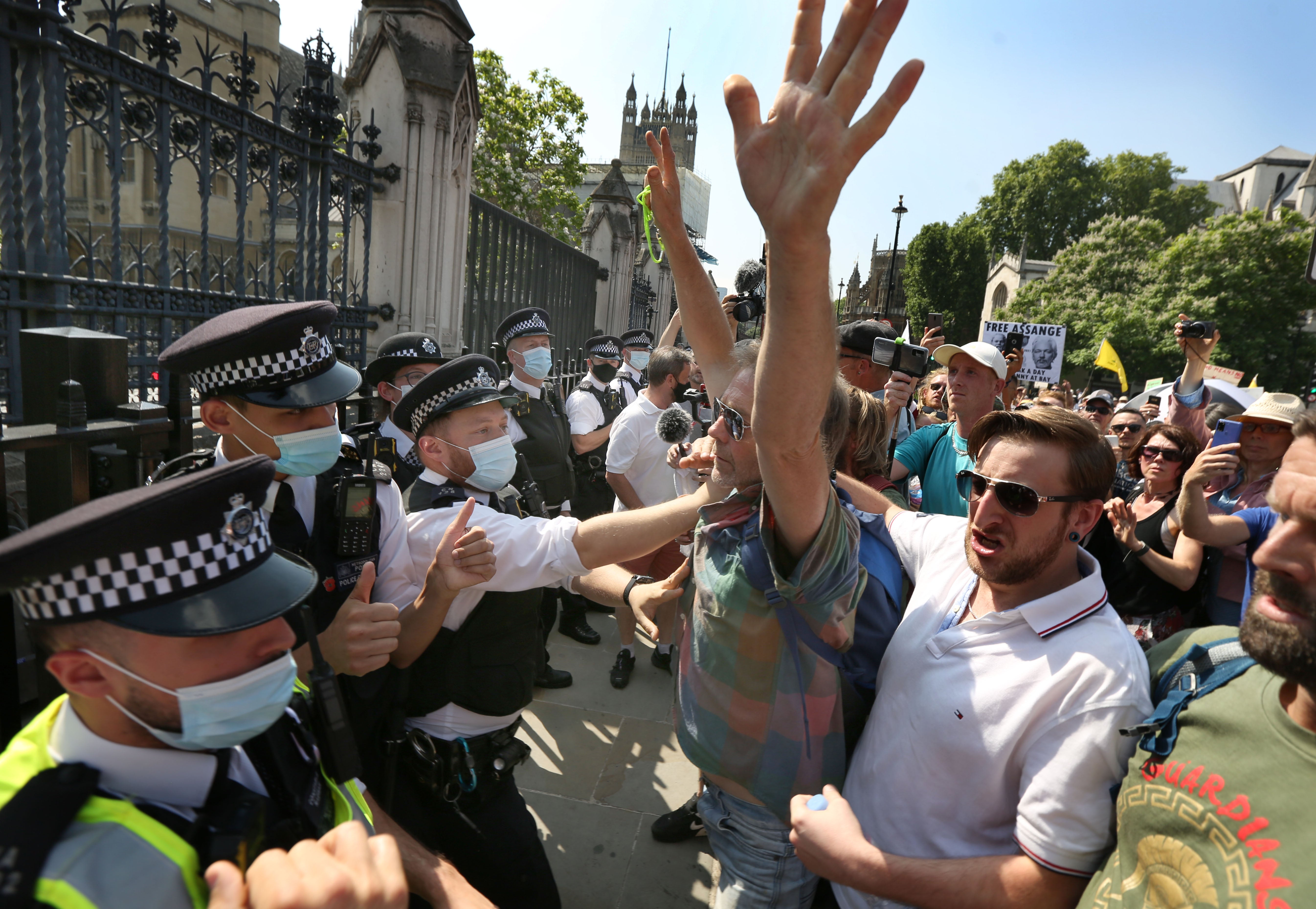 Demonstrators gesture at police officers during a protest against lockdowns and Covid-19 vaccines in Parliament Square