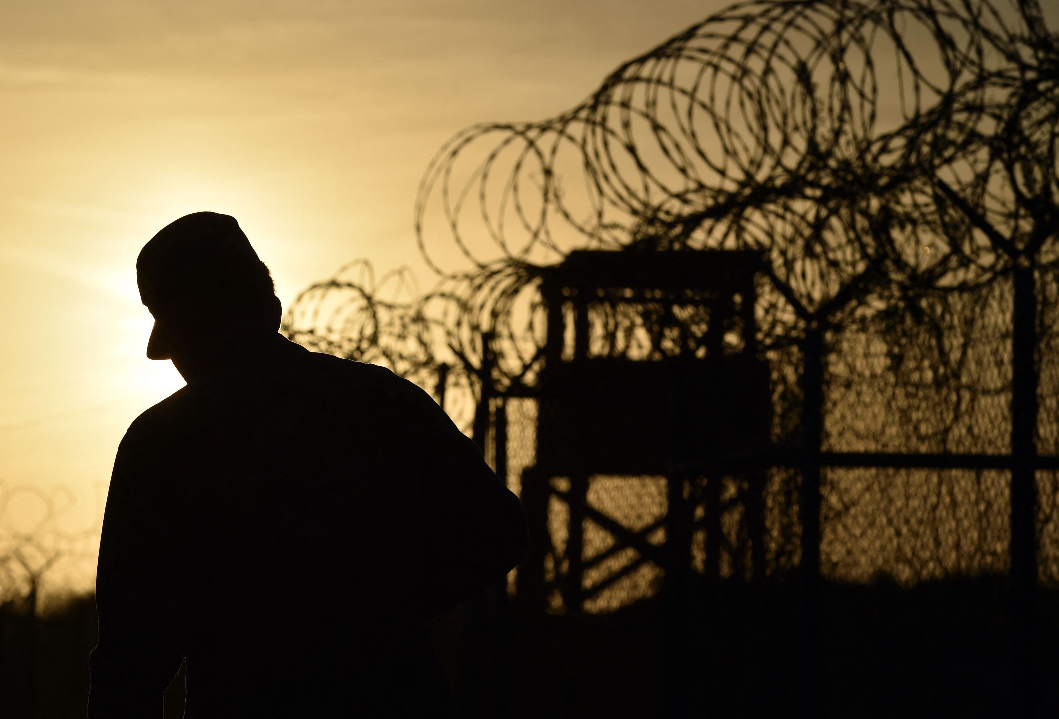 A US soldier walks next to the razor wire-topped fence at the abandoned ‘Camp X-Ray’ detention facility