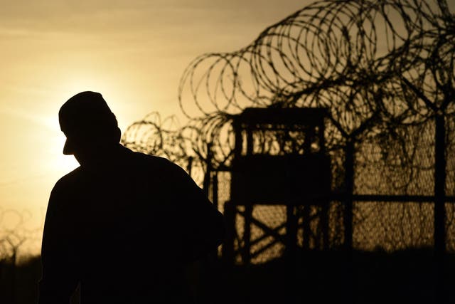 <p>A US soldier walks next to the razor wire-topped fence at the abandoned ‘Camp X-Ray’ detention facility</p>