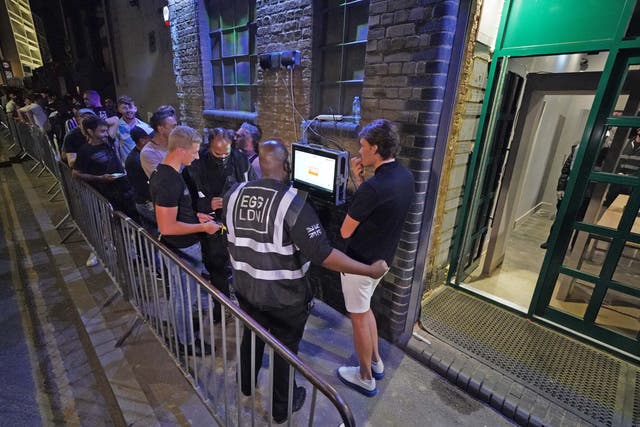 People have their ID checked as they queue up for the Egg nightclub in London
