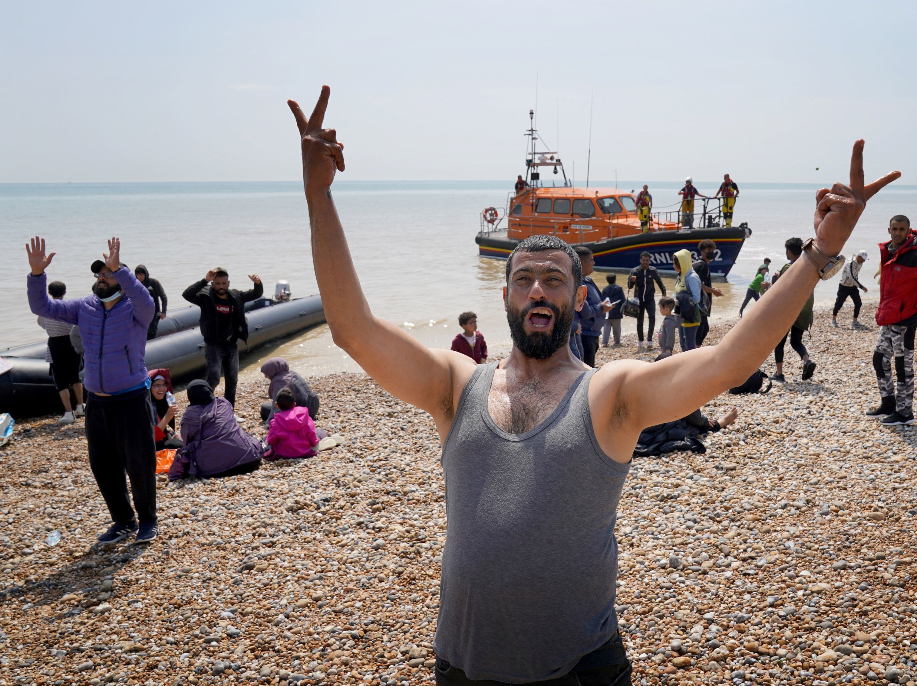 Migrants make their way up the beach after arriving on a small boat at Dungeness in Kent