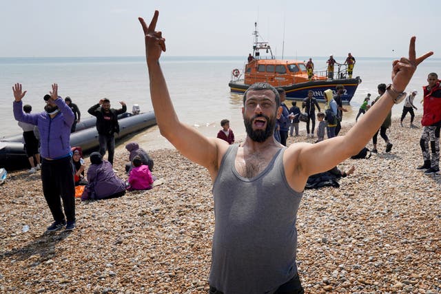 <p>Migrants make their way up the beach after arriving on a small boat at Dungeness in Kent</p>