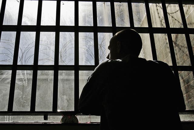 <p>An inmate looks out of the window of the Young Offenders Institution attached to Norwich Prison in 2005</p>