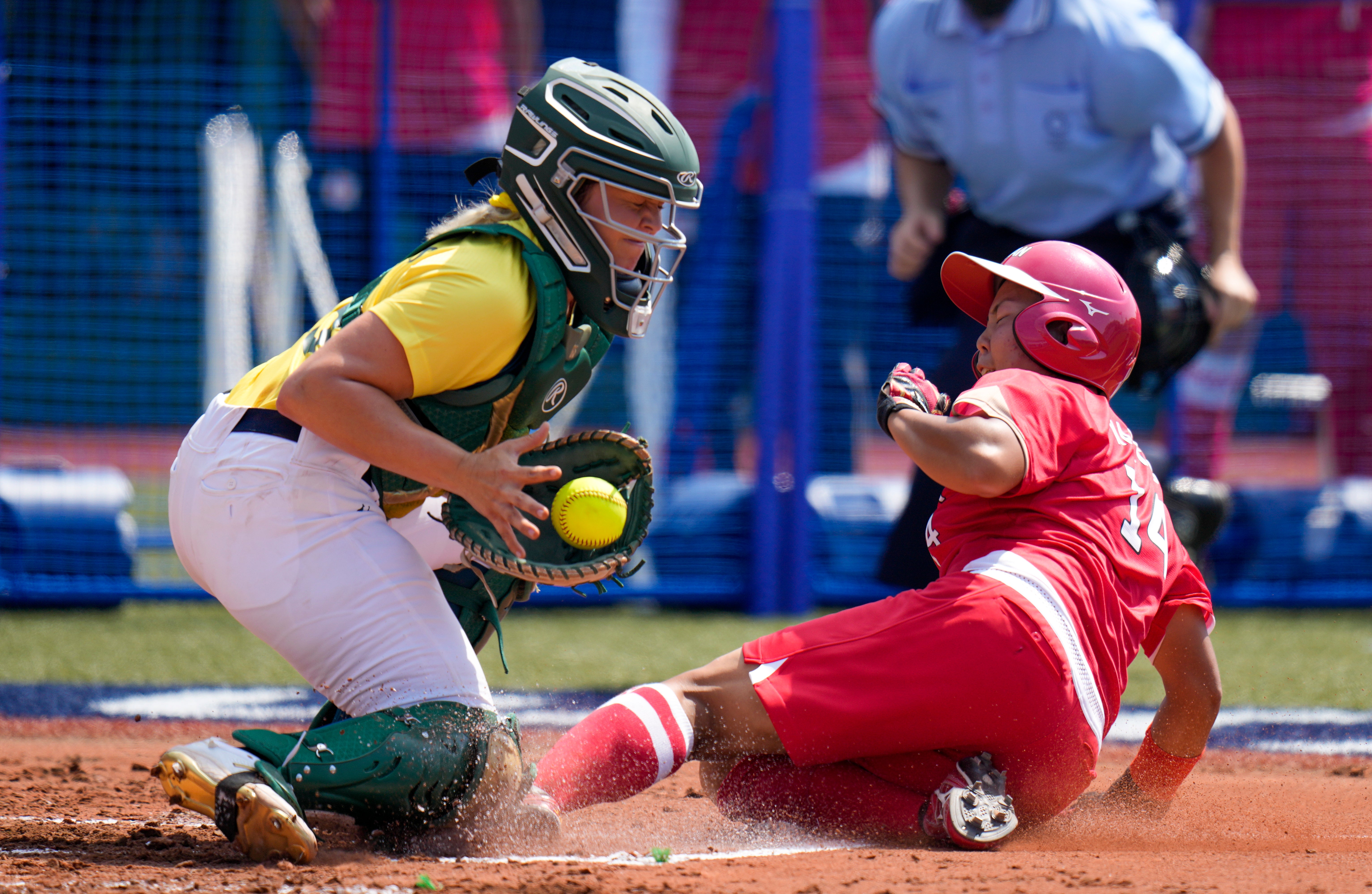 A Japan player slides onto base as an Australia player catches the softball