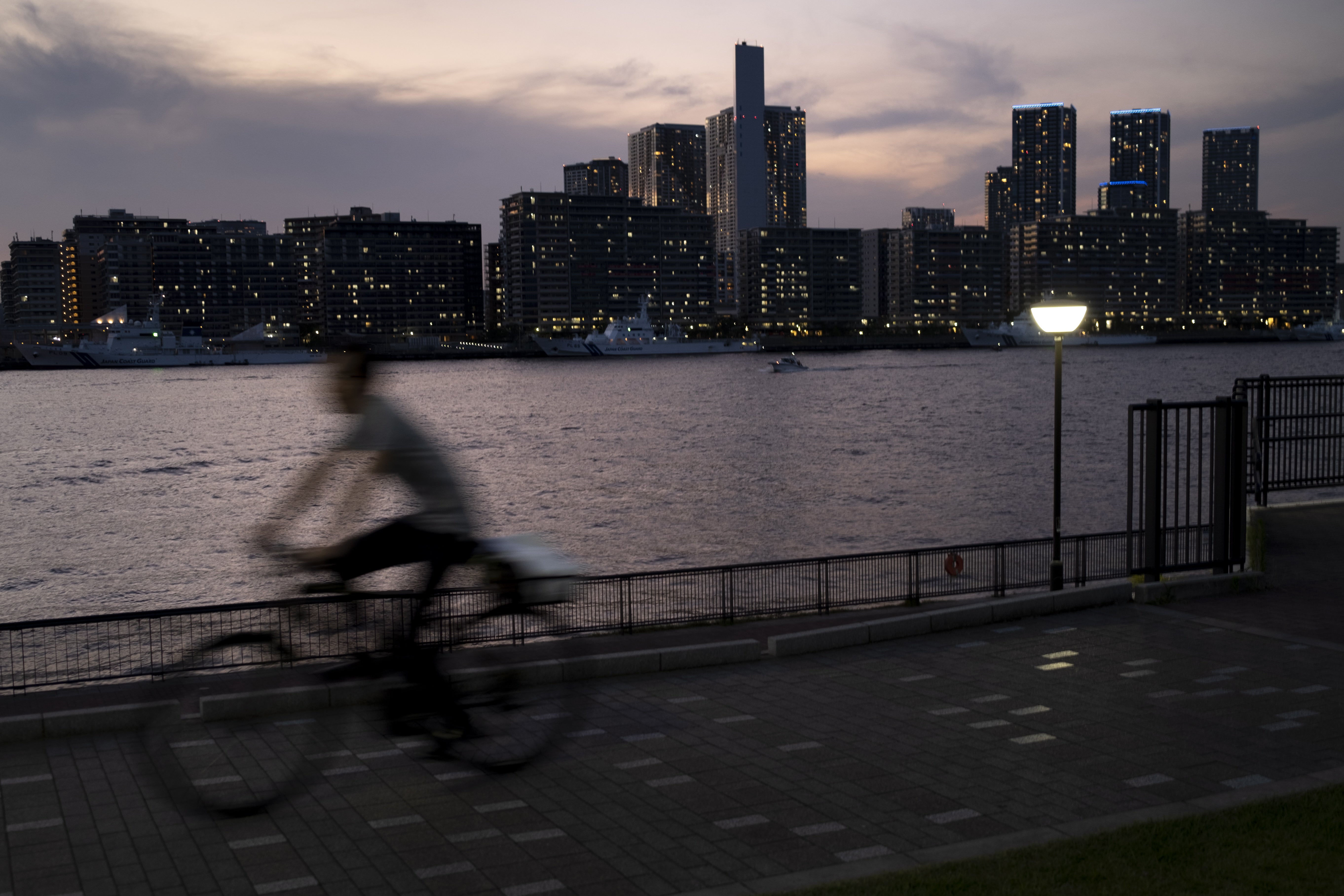 A person rides a bicycle in front of the Olympic village in Tokyo