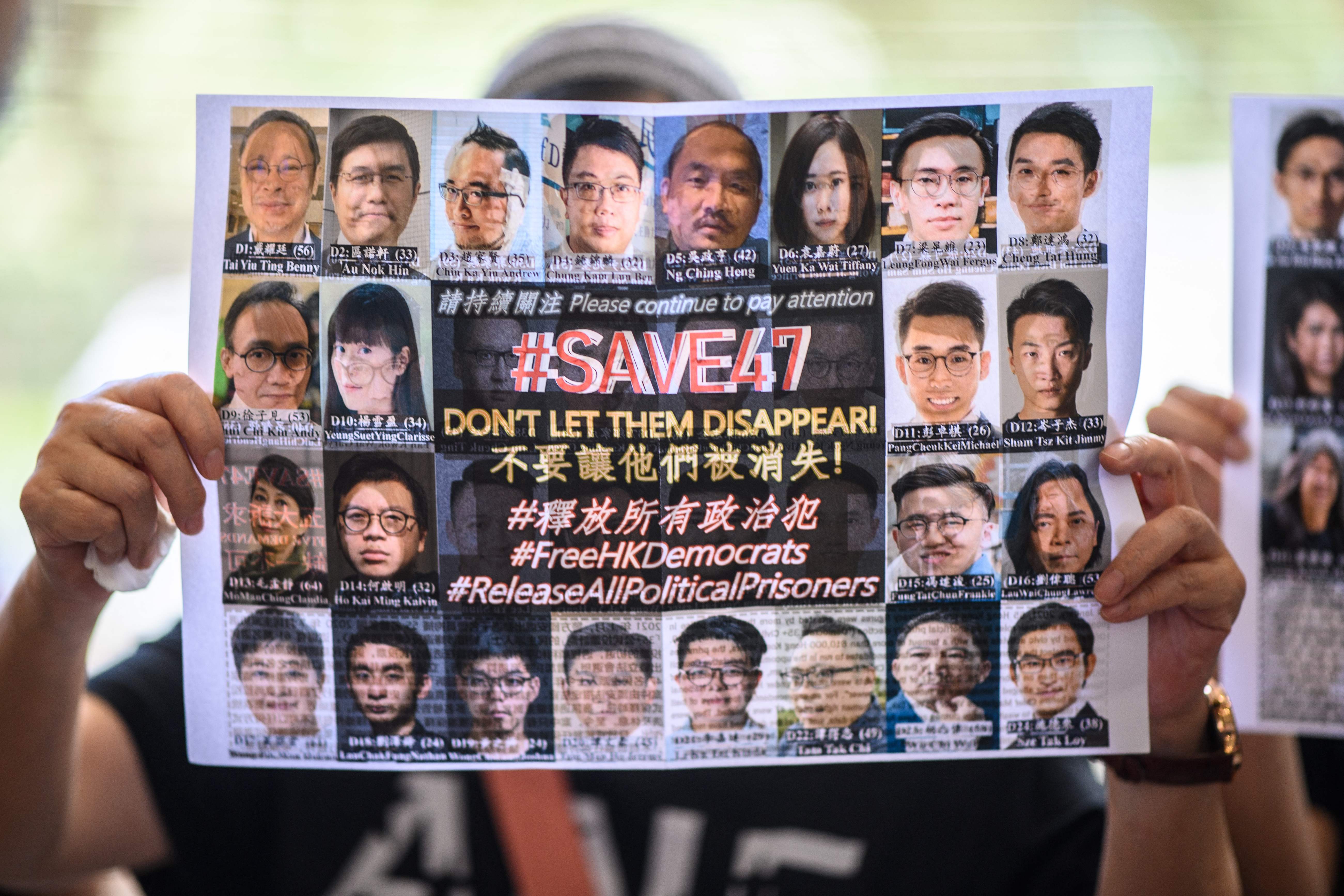 A supporter holds a poster showing some of the 47 pro-democracy activists on trial at the West Kowloon Court in Hong Kong