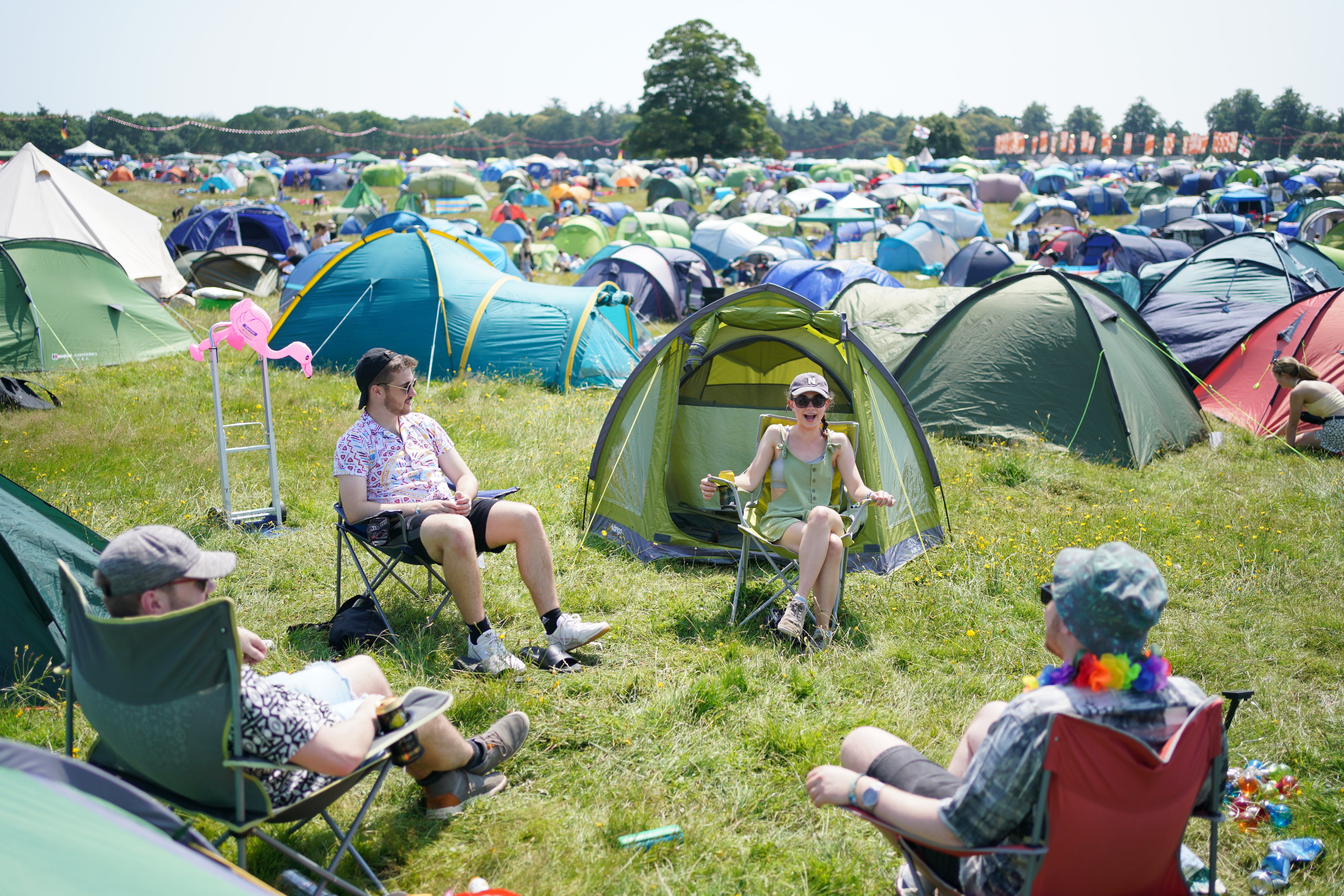 Festivalgoers sit amongst their tents at the Latitude festival in Henham Park, Southwold, Suffolk. Picture date: Thursday July 22, 2021.