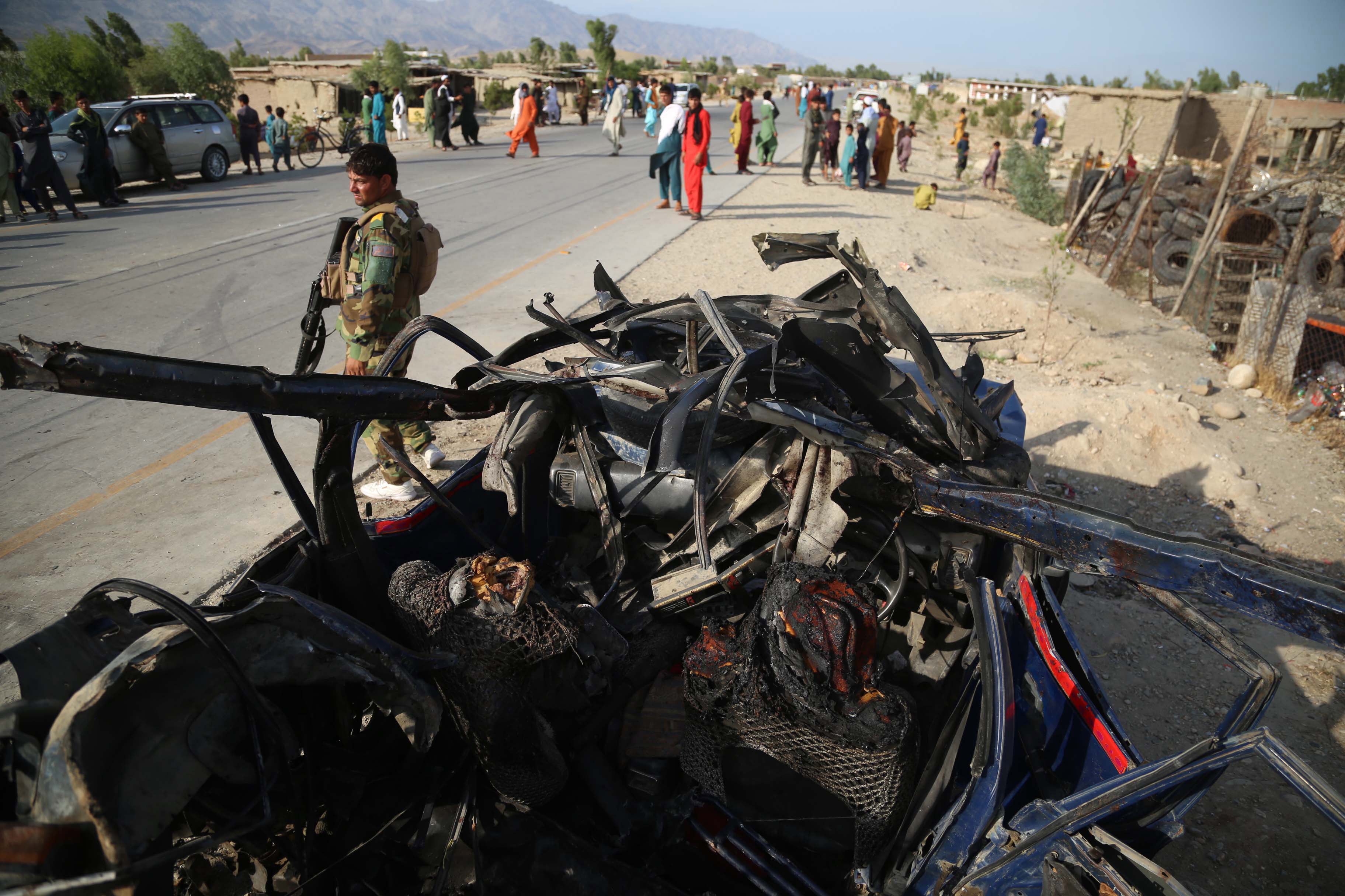 Afghan security officials inspect the scene of a roadside bomb blast that killed six civilians on the outskirts of Jalalabad, Afghanistan