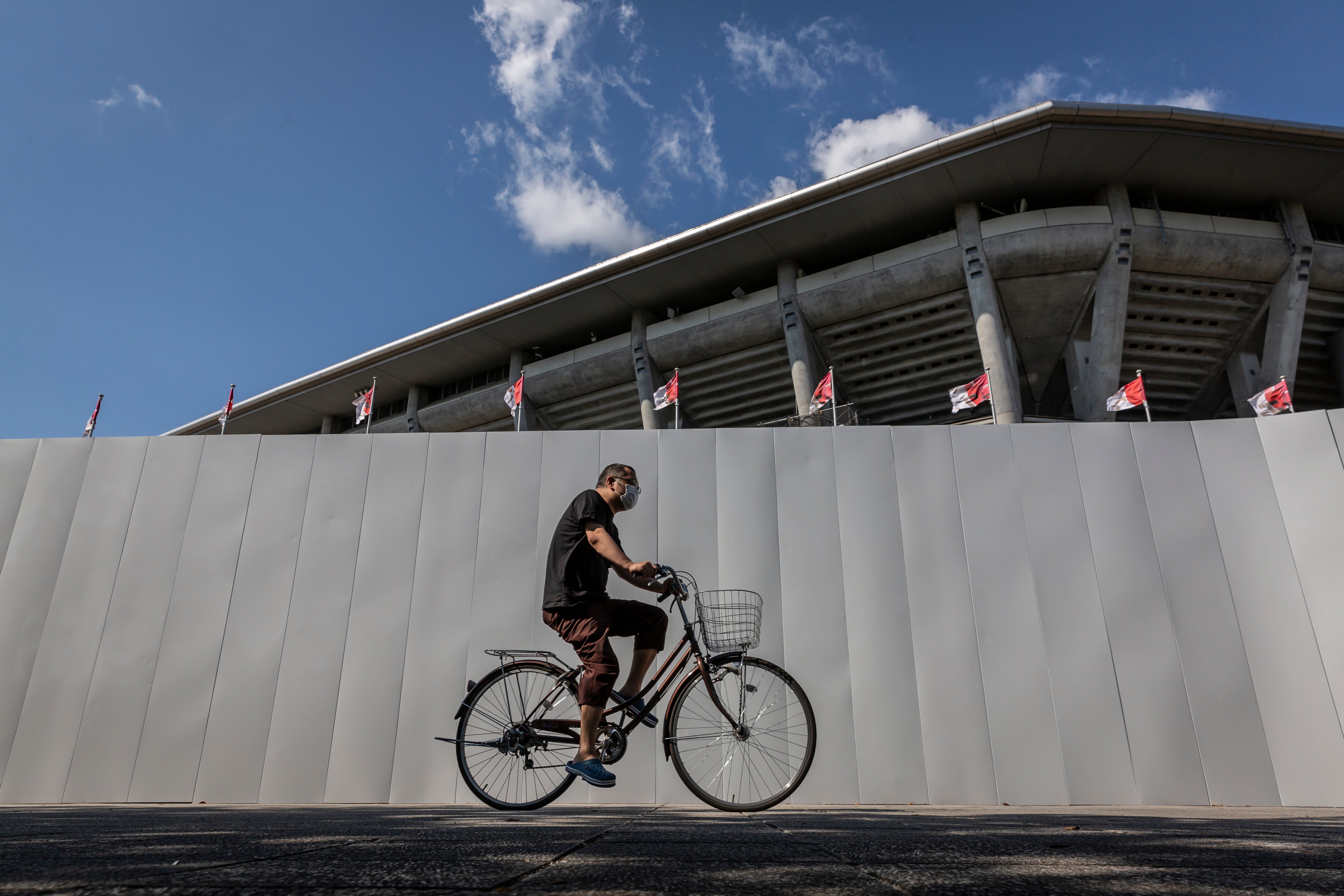 A man cycles past a security wall surrounding the International Stadium Yokohama