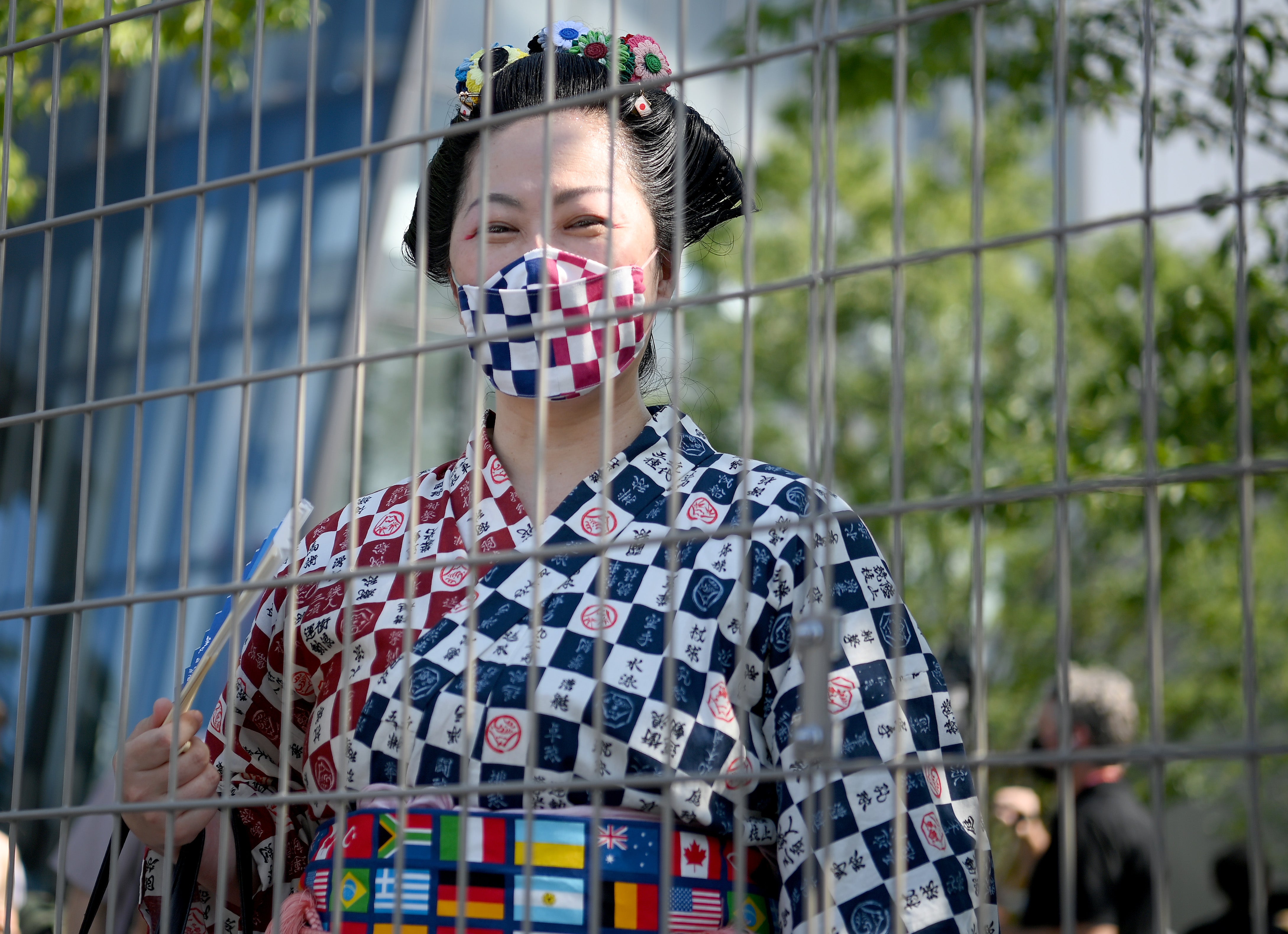 A woman in traditional clothing looks on from behind a fence prior to the Opening Ceremony of the Tokyo 2020 Olympic Games at Olympic Stadium