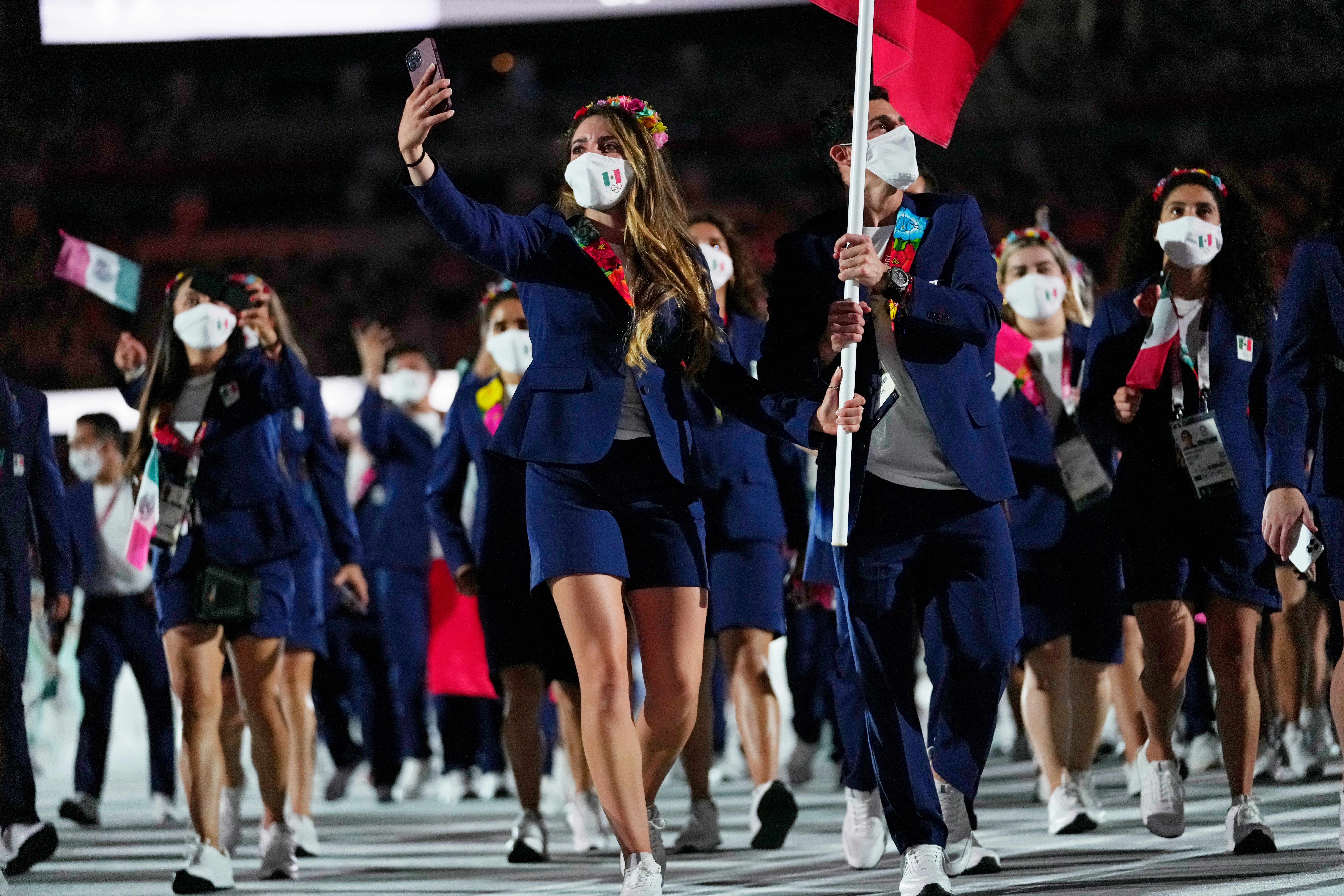 <p>Gaby López y Rommel Pacheco Marrufo, de México, portan la bandera de su país durante la ceremonia de apertura en el Estadio Olímpico de los Juegos Olímpicos de Verano de 2020, el viernes 23 de julio de 2021 en Tokio, Japón.</p>