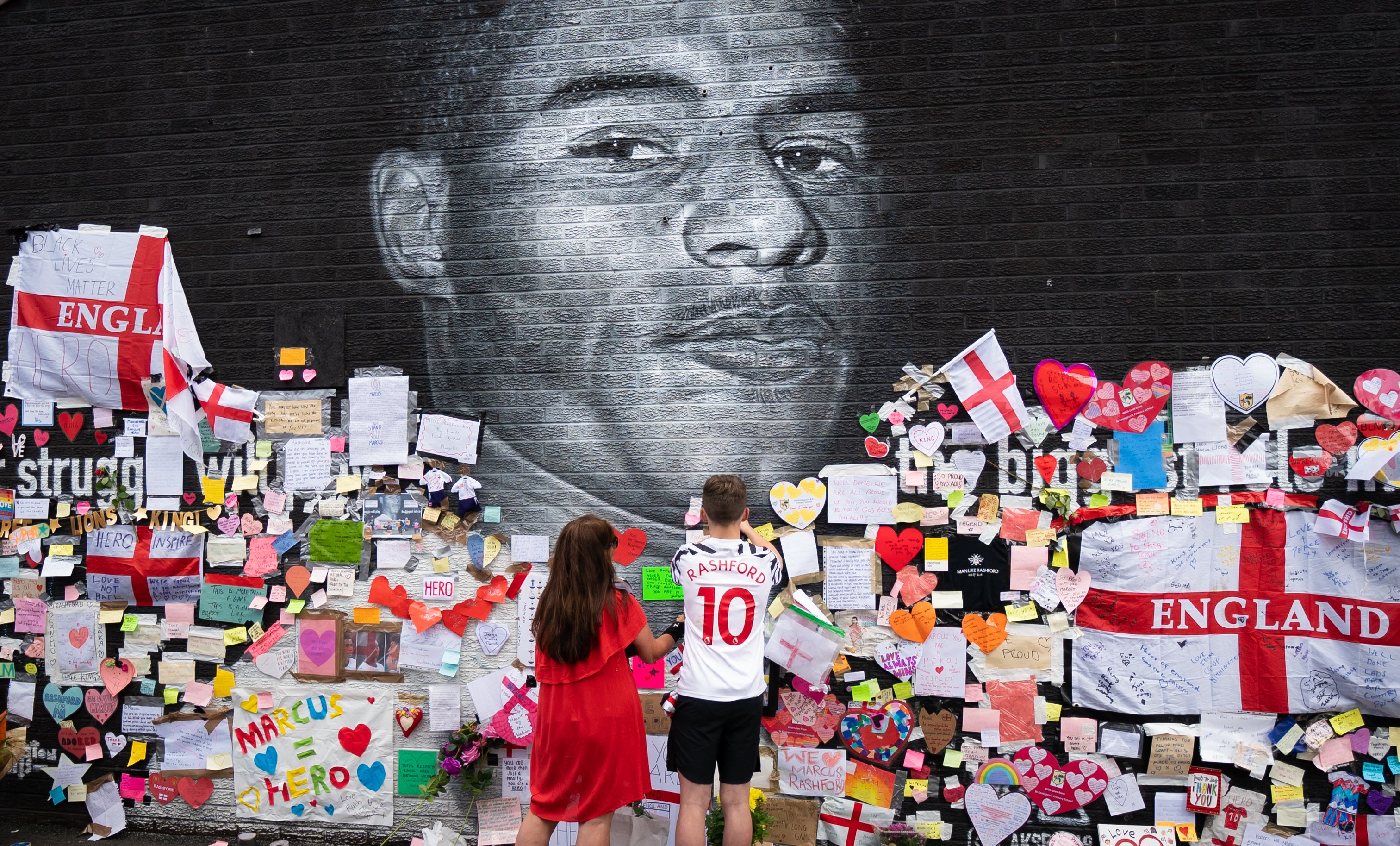 Mackenzie Robertson and his mother Sally Coles-Robertson put up a message on the mural of Manchester United striker and England player Marcus Rashford in Withington (Danny Lawson/PA)