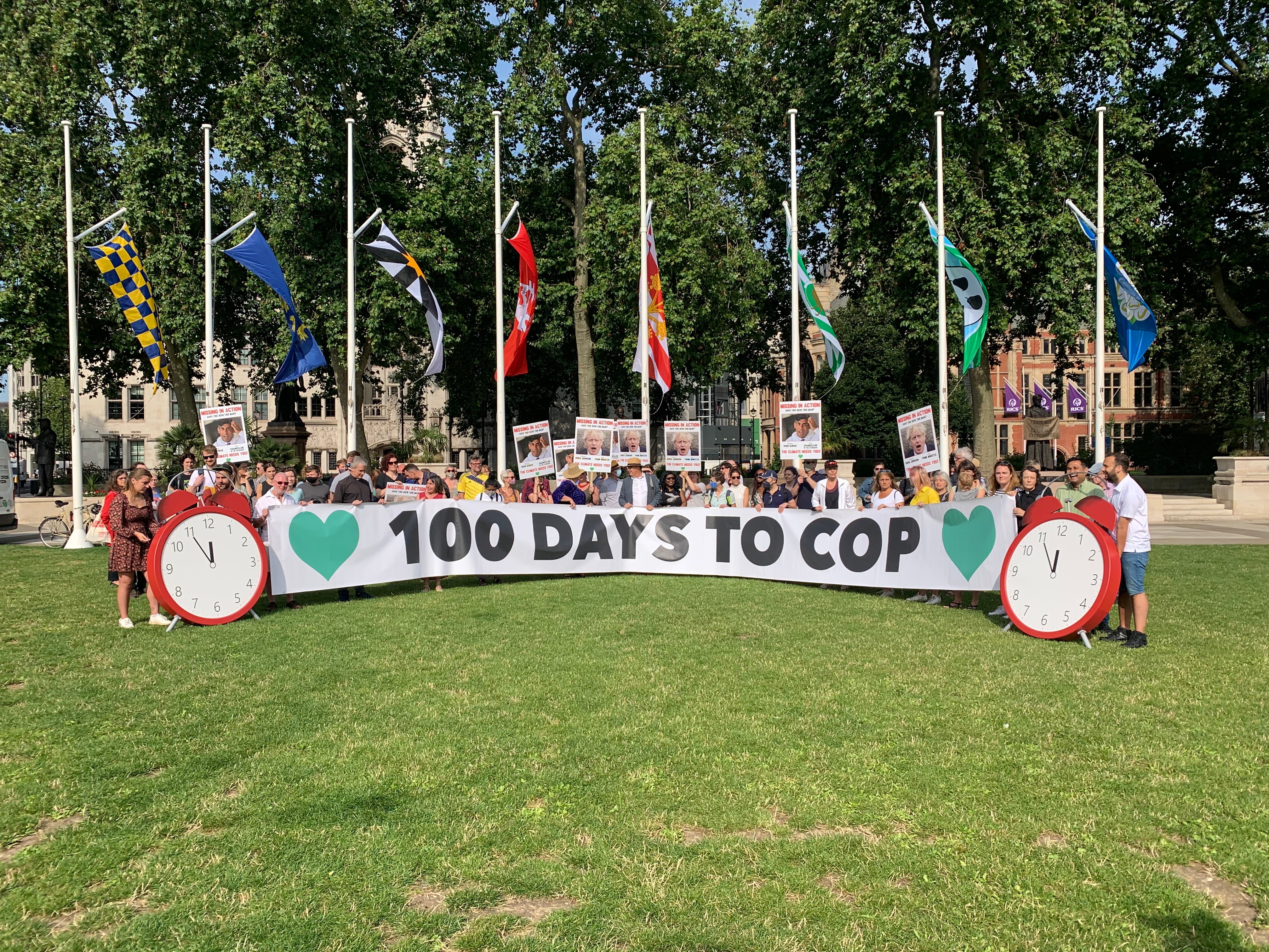 Climate campaigners gather in Parliament Square, behind a giant banner calling for action 100 days before the Cop26 summit