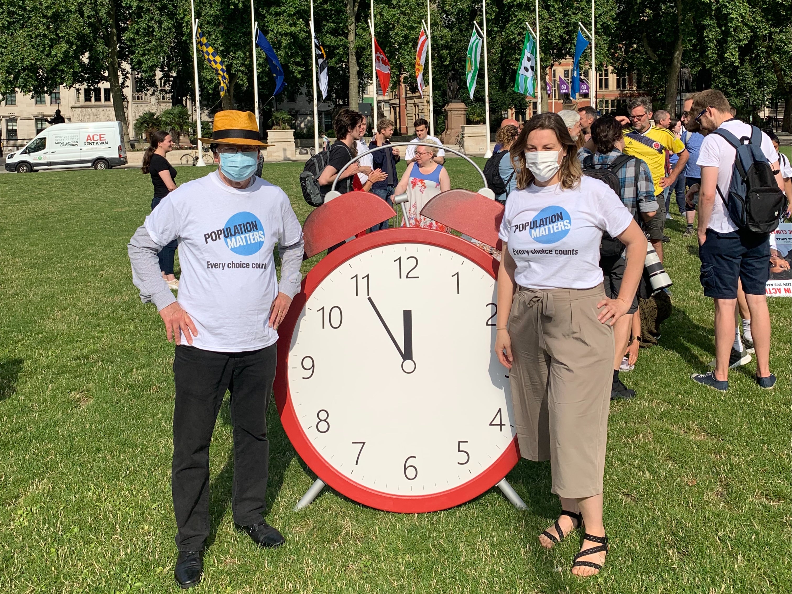 Attendees stand behind lifesize alarm clocks, designed to show time is running out in the climate emergency
