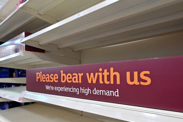 <p>A sign requesting shoppers' patience about products temporarily out of stock is displayed on empty shelves</p>