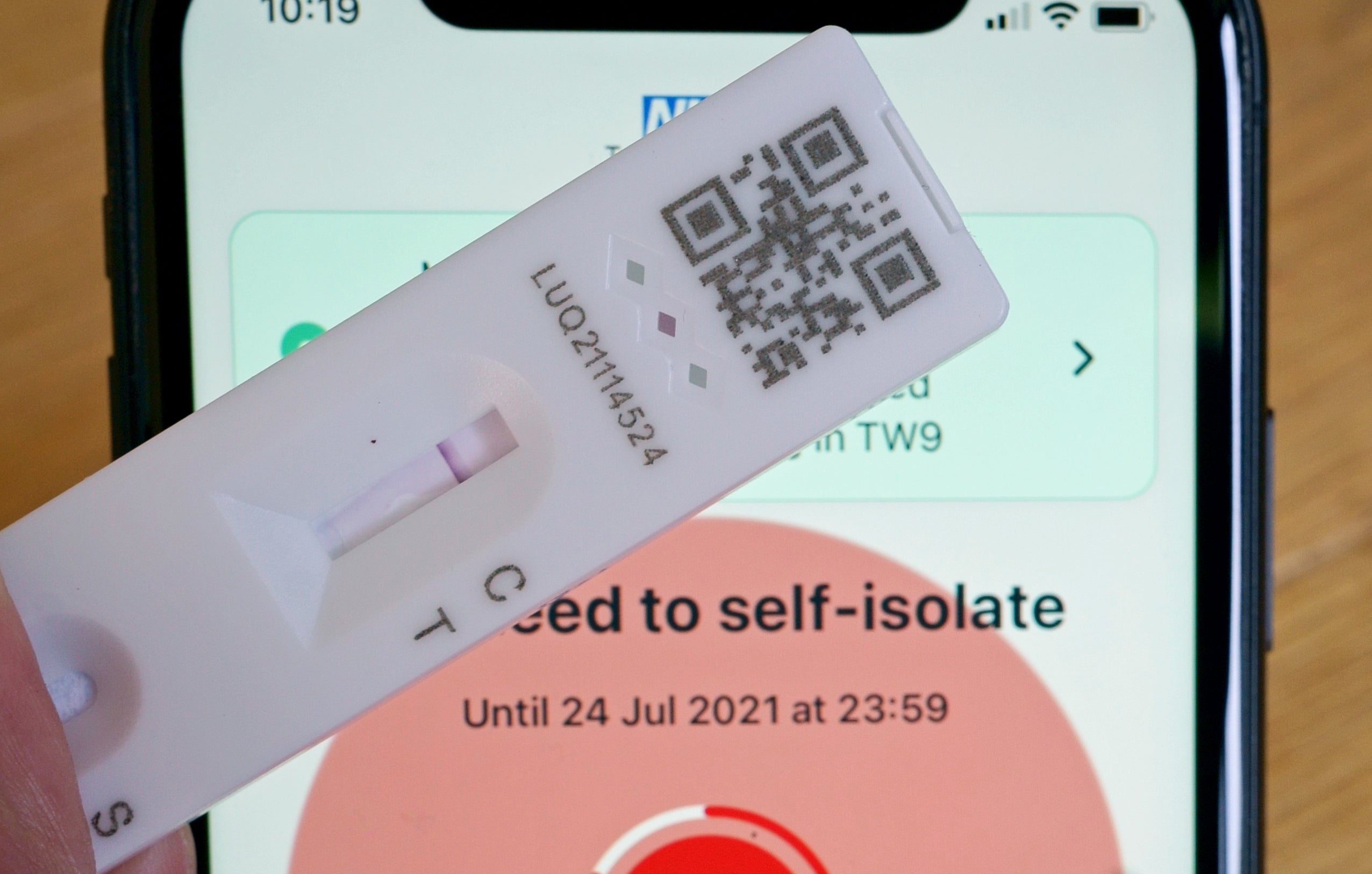 A negative lateral flow test next to advice from the NHS Covid app to self-isolate
