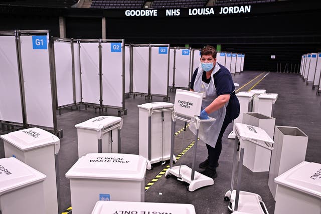 <p>An NHS worker gathers clinical waste bins as Scotland’s temporary NHS Louisa Jordan site is shut down</p>