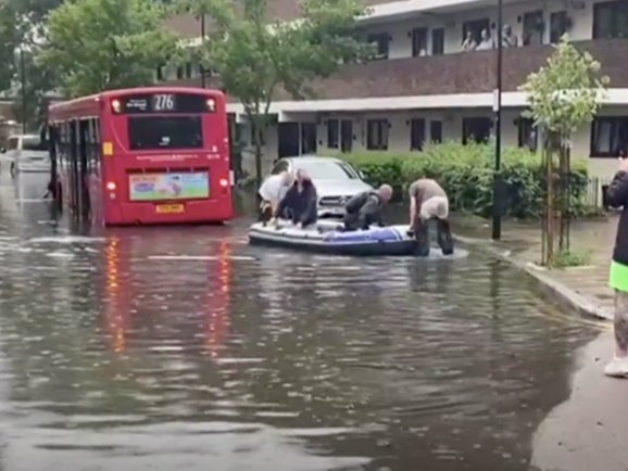 <p>Passengers are rescued from standed bus by inflatable dinghy in London’s Hackney Wick</p>