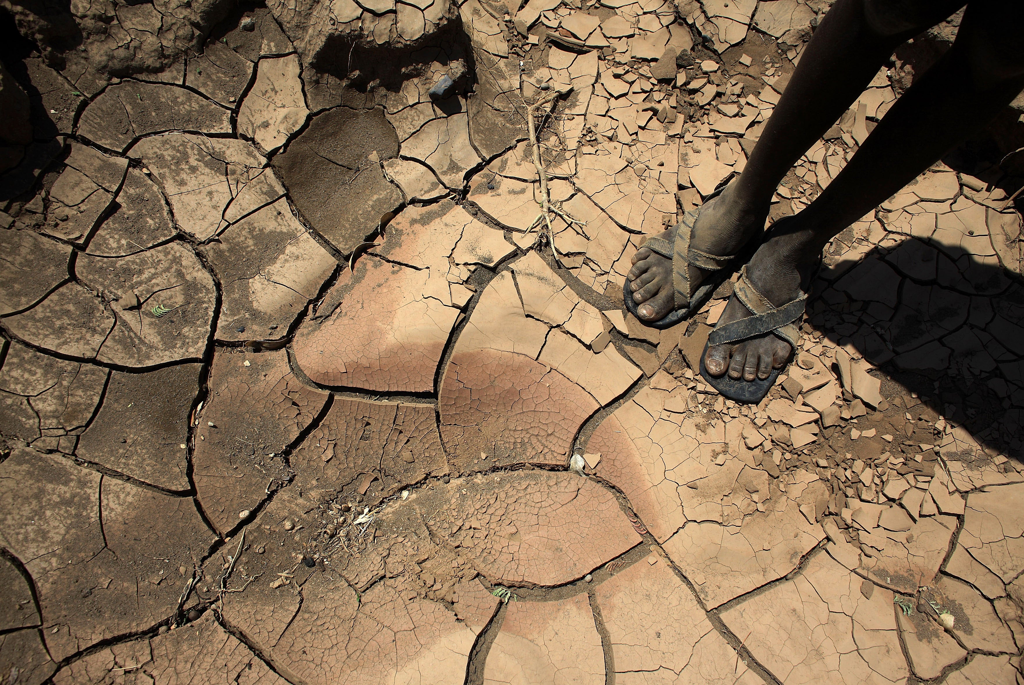 A boy from a remote tribe stands on a dried-up river bed in Kenya made worse by climate change