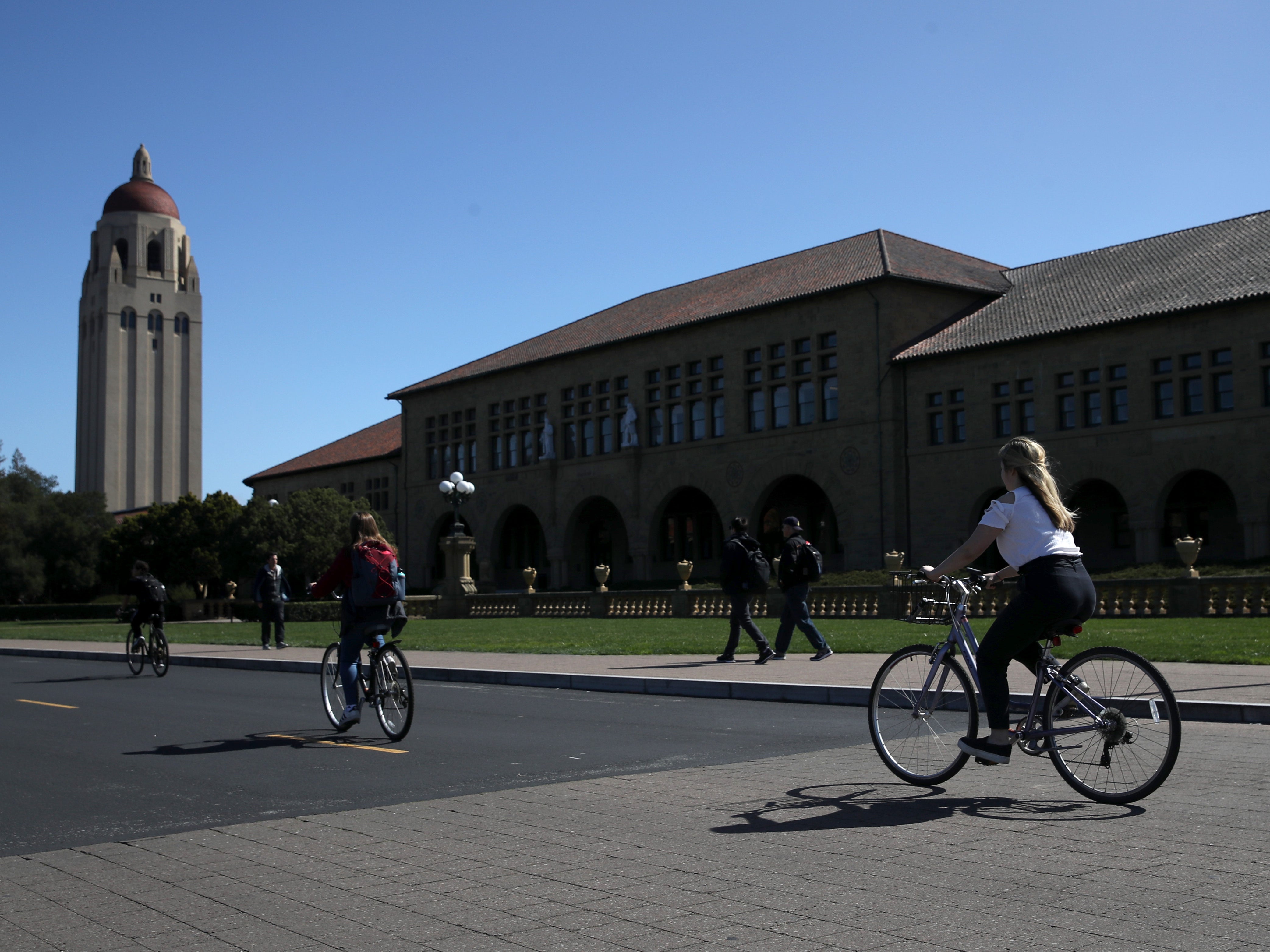 <p>Cyclists ride by Hoover Tower on the Stanford University campus on 12 March 2019 in Stanford, California</p>