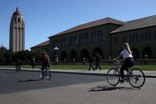 <p>Cyclists ride by Hoover Tower on the Stanford University campus on 12 March 2019 in Stanford, California</p>