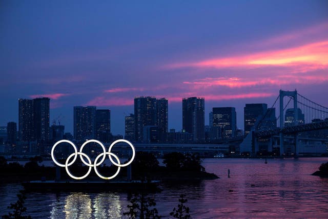 <p>A general view shows the Olympic rings lit up at dusk, with the Rainbow bridge in the background, on the Odaiba waterfront in Tokyo</p>