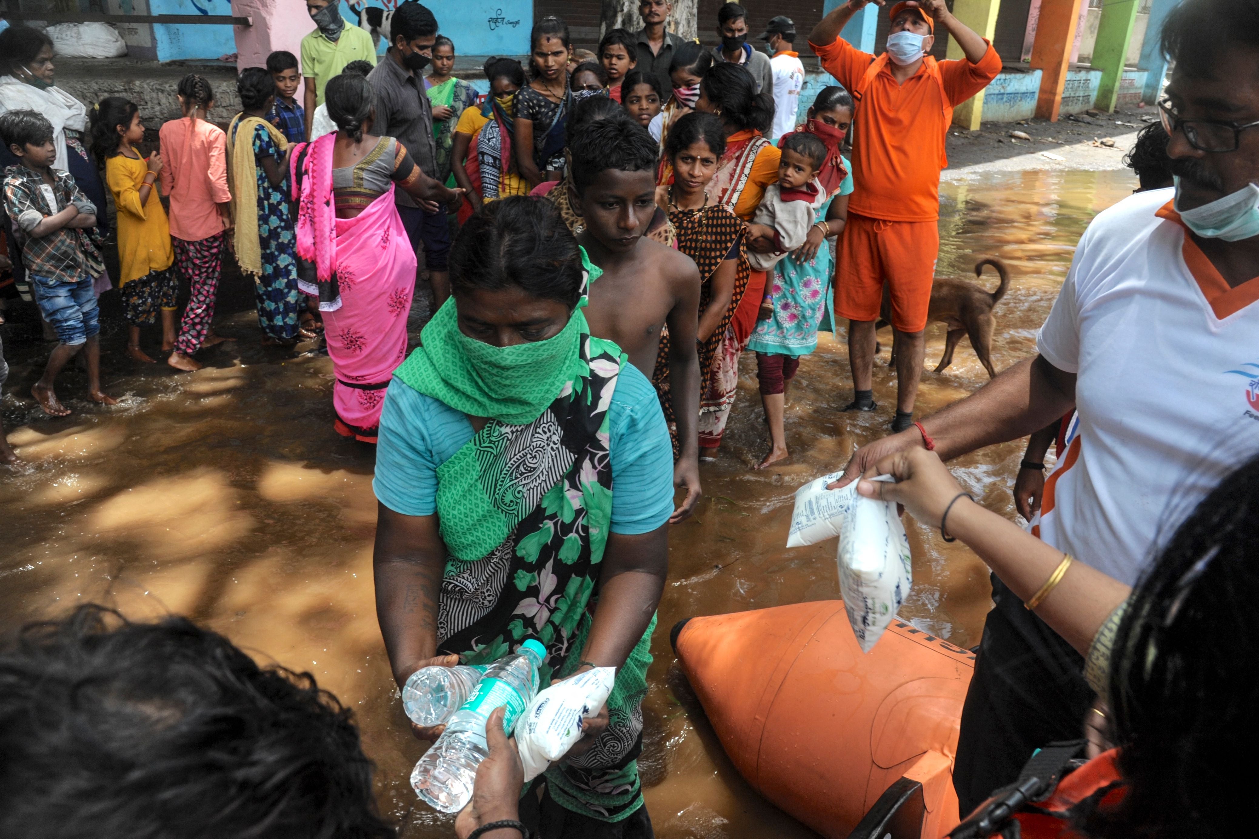 India's National Disaster Response Force (NDRF) personnel distribute food and relief material to people impacted by floods in Maharashtra