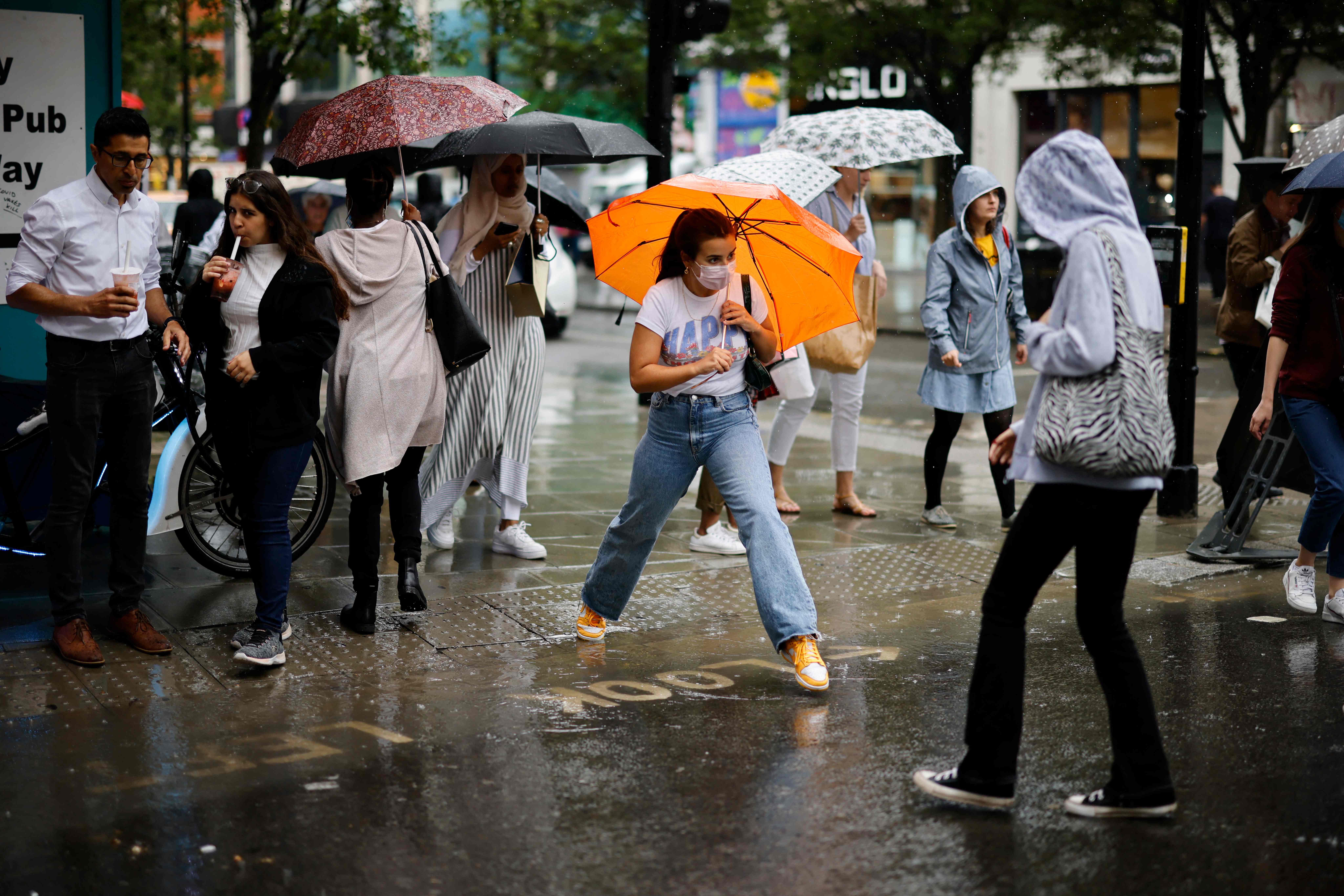 <p>A pedestrian jumps a puddle as they cross the road during heavy rain in central London</p>