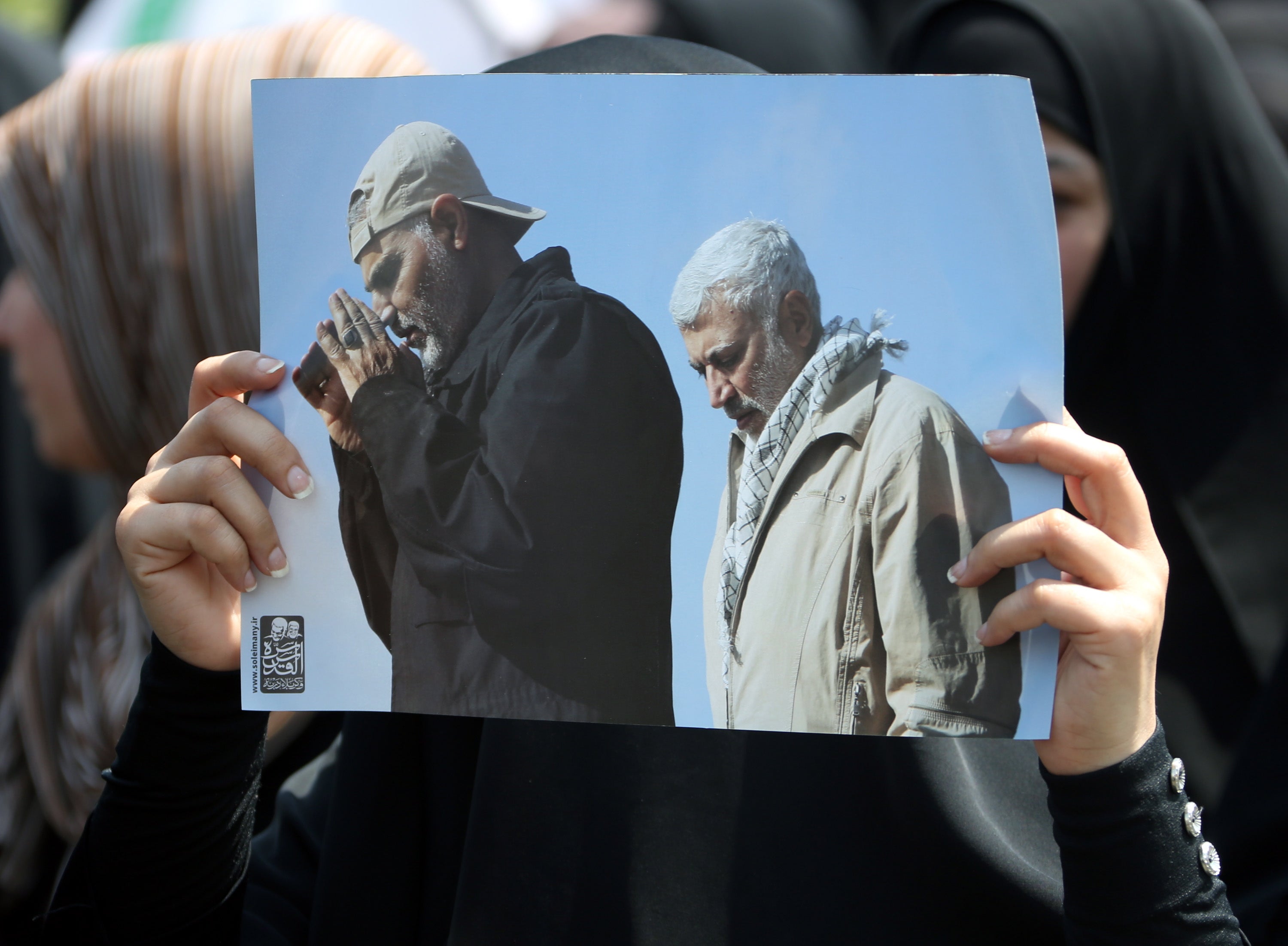 A supporter of Iran-backed Iraqi Shiite armed groups popular mobilisation forces carries the pictures of slain Abu Mahdi al-Muhandis and General Qassem Soleimani during a symbolic funeral