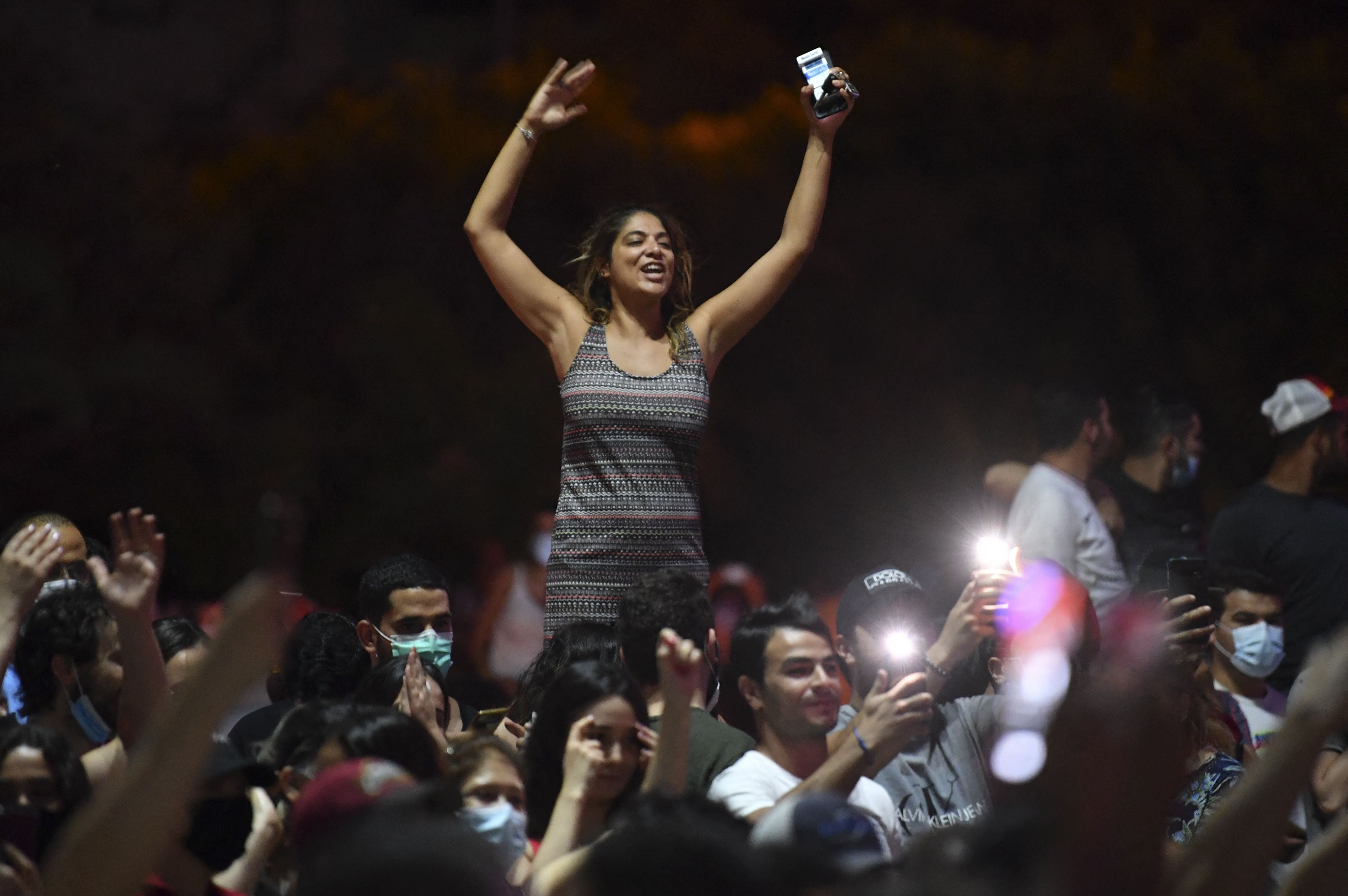 People celebrate in the street after Tunisian President Kais Saied announced the dissolution of parliament and Prime Minister Hichem Mechichi's government in Tunis on July 25