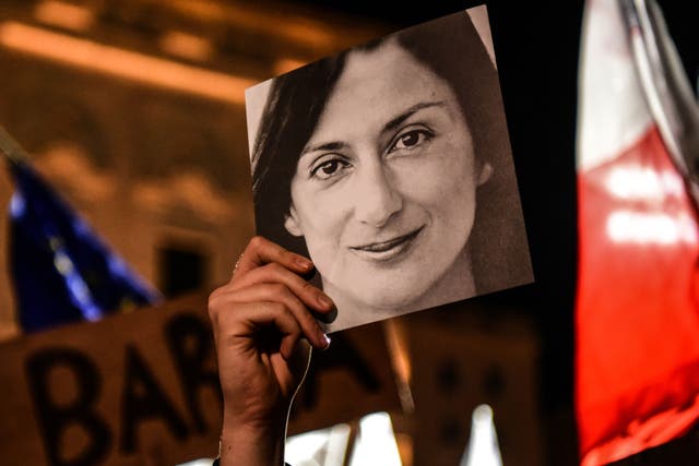 <p>A person holds a photo of the killed journalist Daphne Caruana Galizia, during a protest in 2019 in Valletta</p>