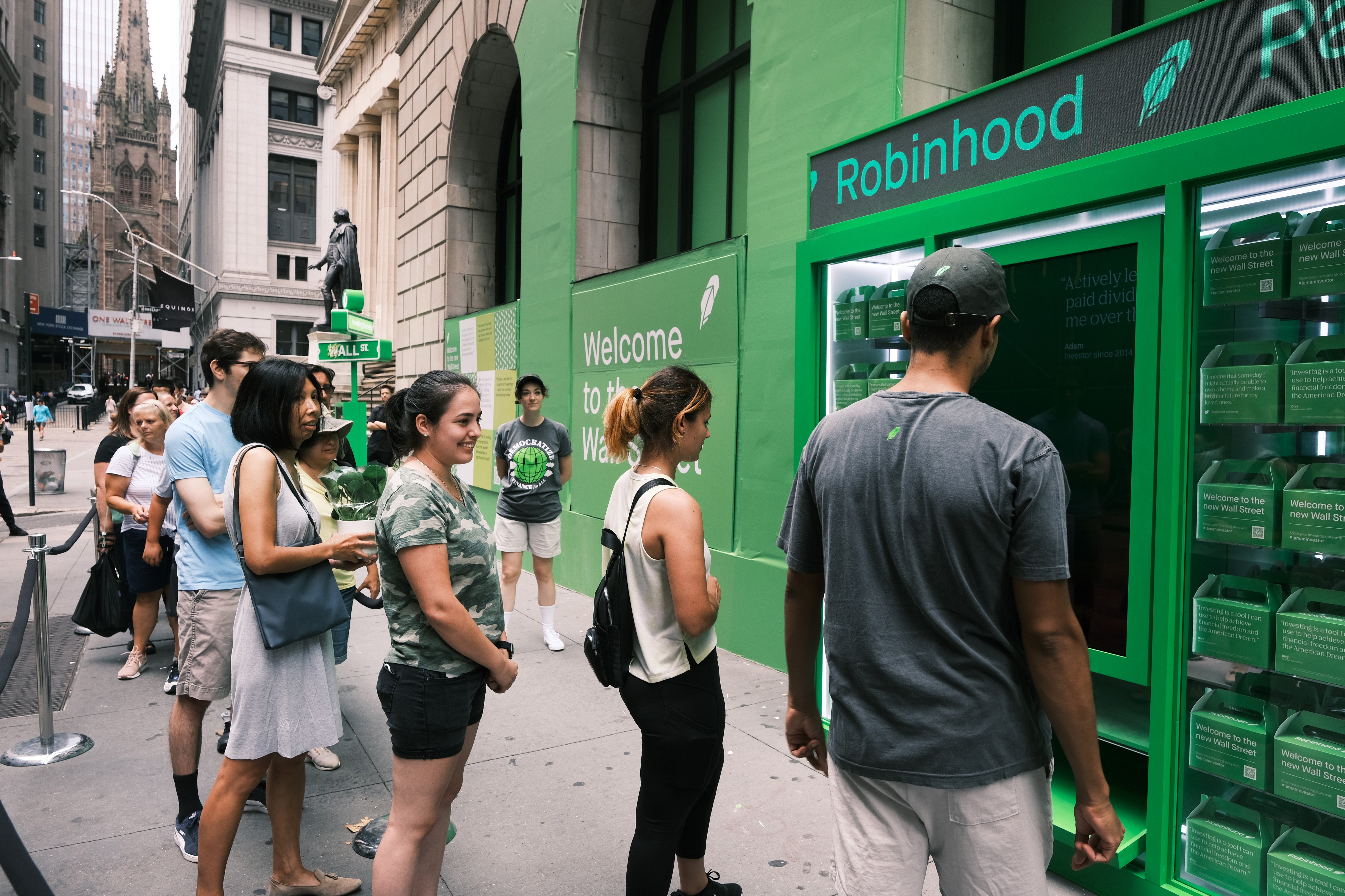 People wait in line for T-shirts at a pop-up kiosk for the online brokerage Robinhood along Wall Street after the company went public with an IPO