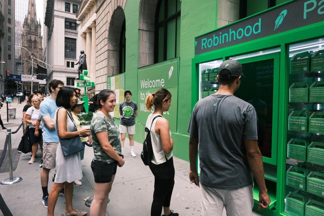 <p>People wait in line for T-shirts at a pop-up kiosk for the online brokerage Robinhood along Wall Street after the company went public with an IPO </p>