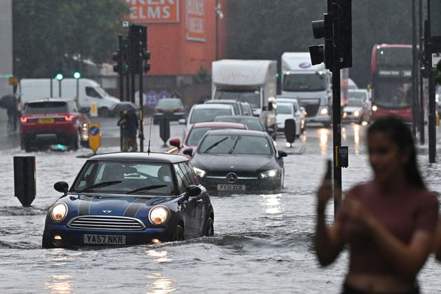 <p>Drivers negotiate flooded roads in southwest London last week</p>