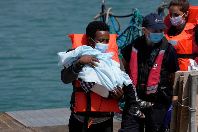 <p>A man and a child are disembarked from a British border force vessel in Dover</p>