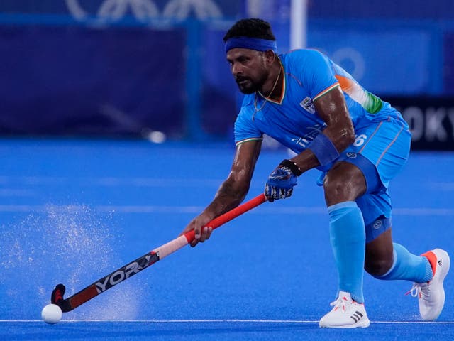 <p>India’s Birendra Lakra plays a pass against Japan as water sprays up from the artificial surface</p>