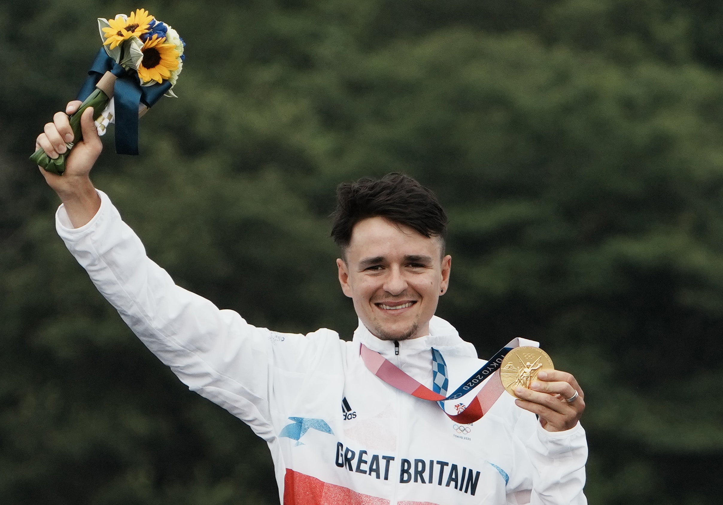 Tom Pidcock raises his gold medal aloft