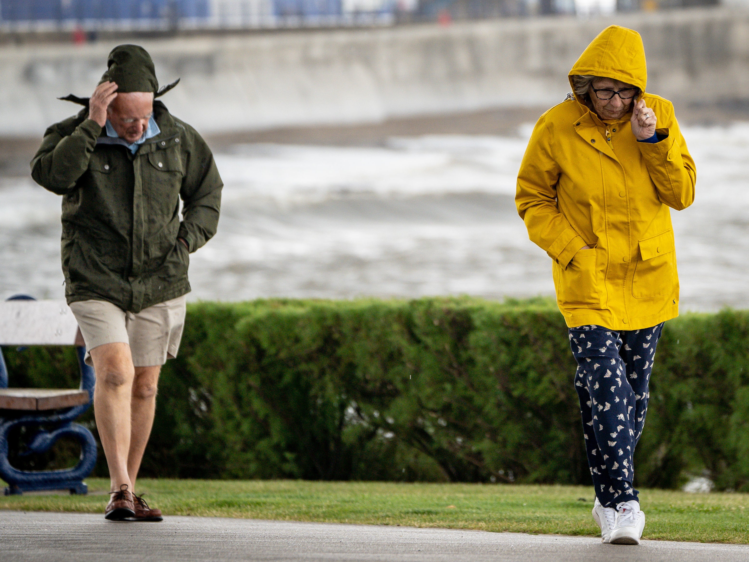 <p>People pull down their hoods to shelter from the wind as they walk along the sea front in Porthcawl, Wales</p>