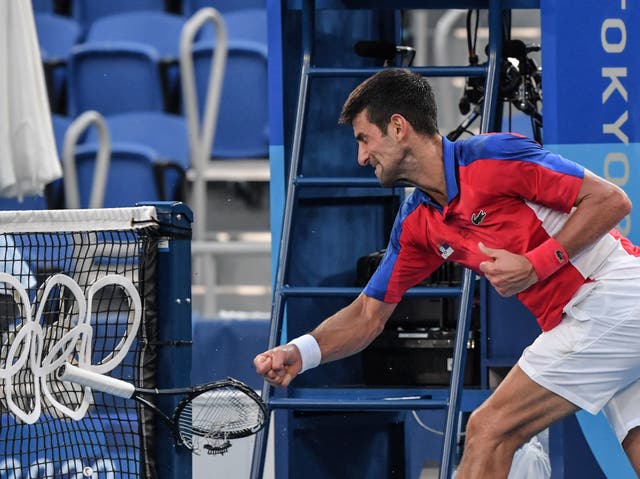 <p>Novak Djokovic smashes a racket against the net, having hurled another into the empty stands</p>
