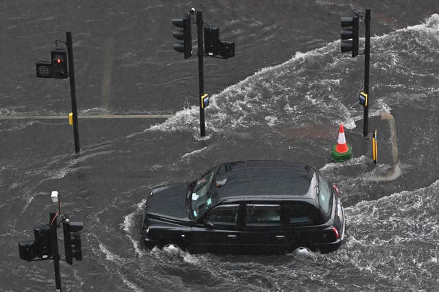 <p>A London taxi drives through water during flash floods in July</p>