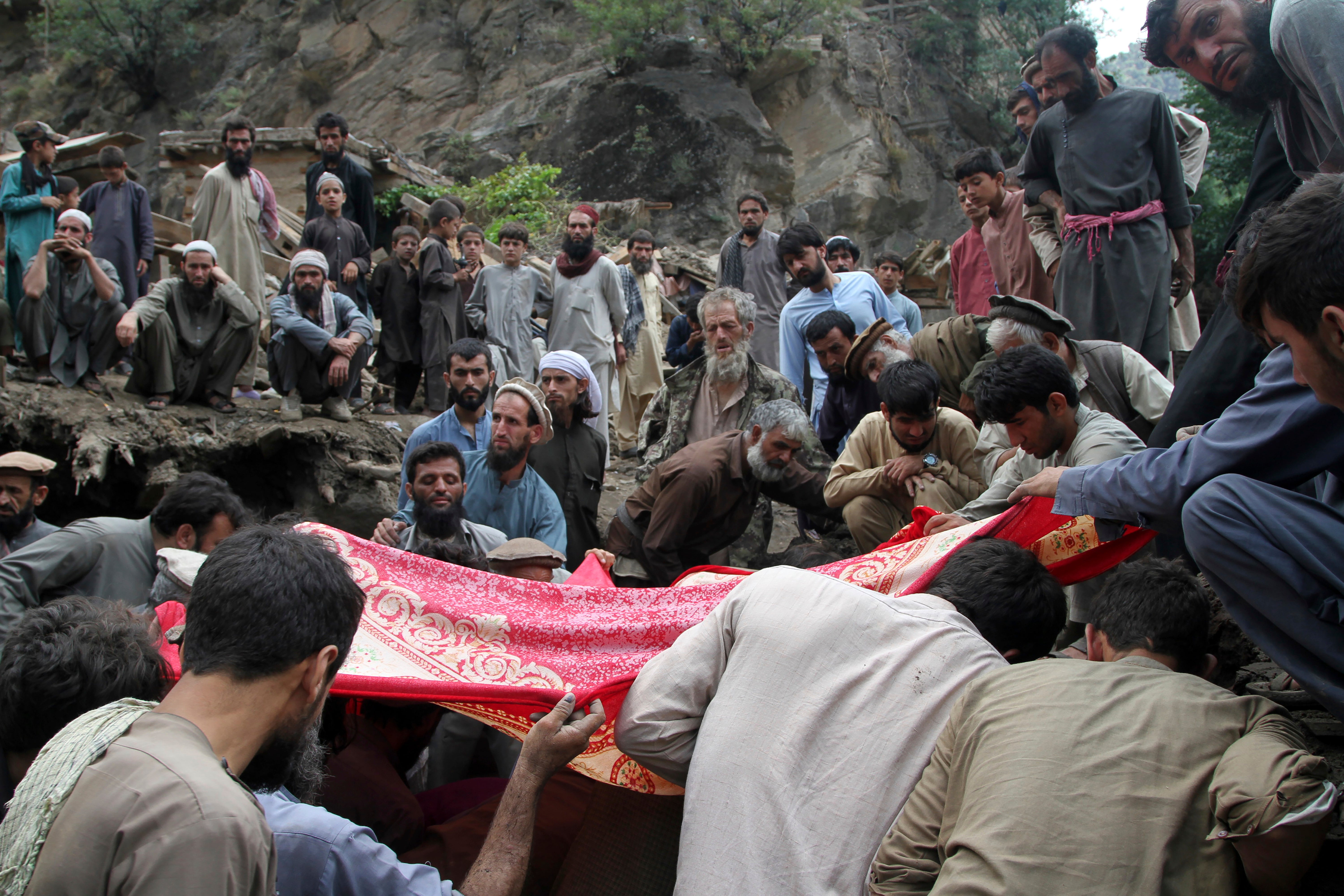 Locals search for victims of a mudslide following heavy flooding in Nuristan